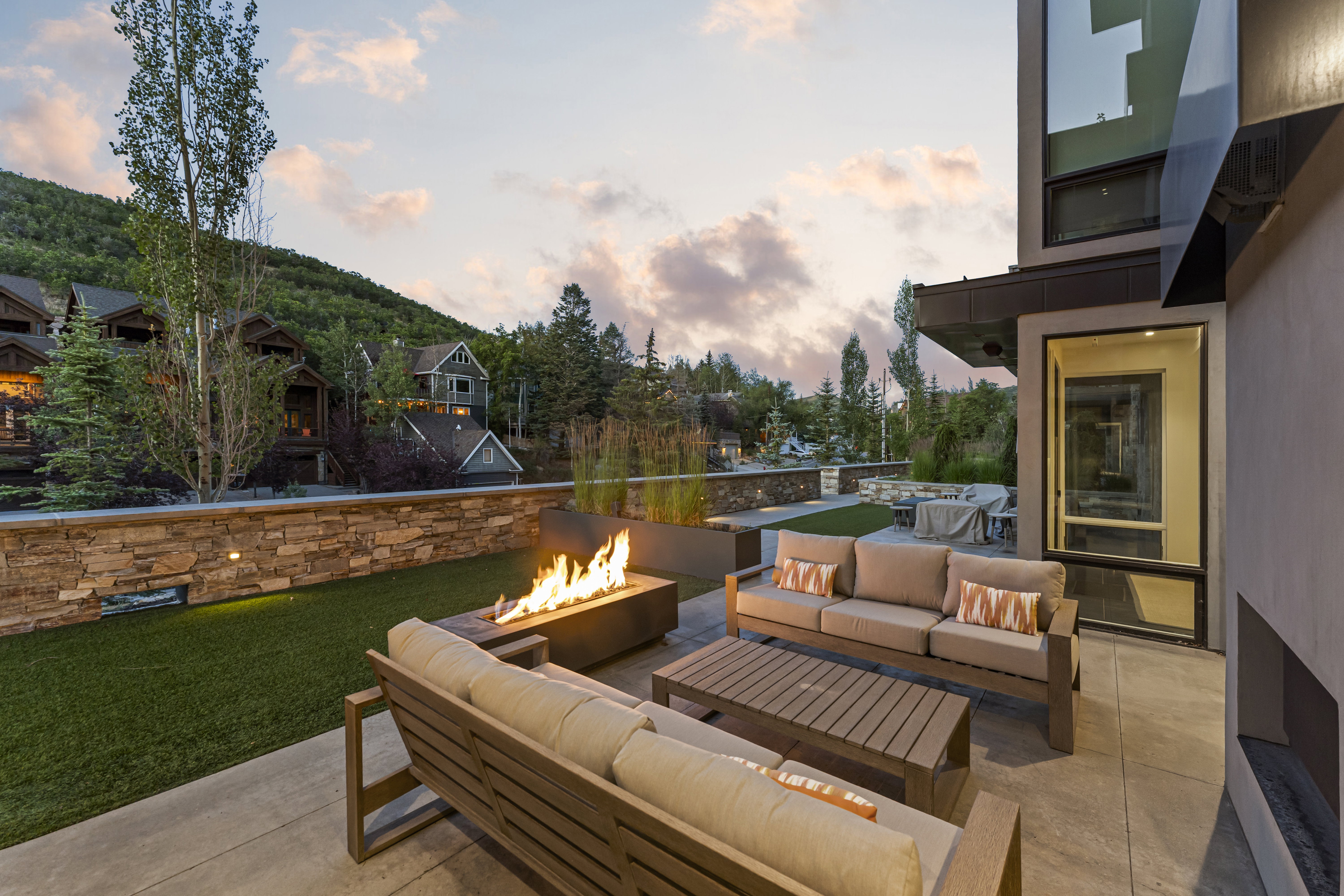 Spacious outdoor patio featuring a built-in fire pit, concrete pavers, and an artificial turf area