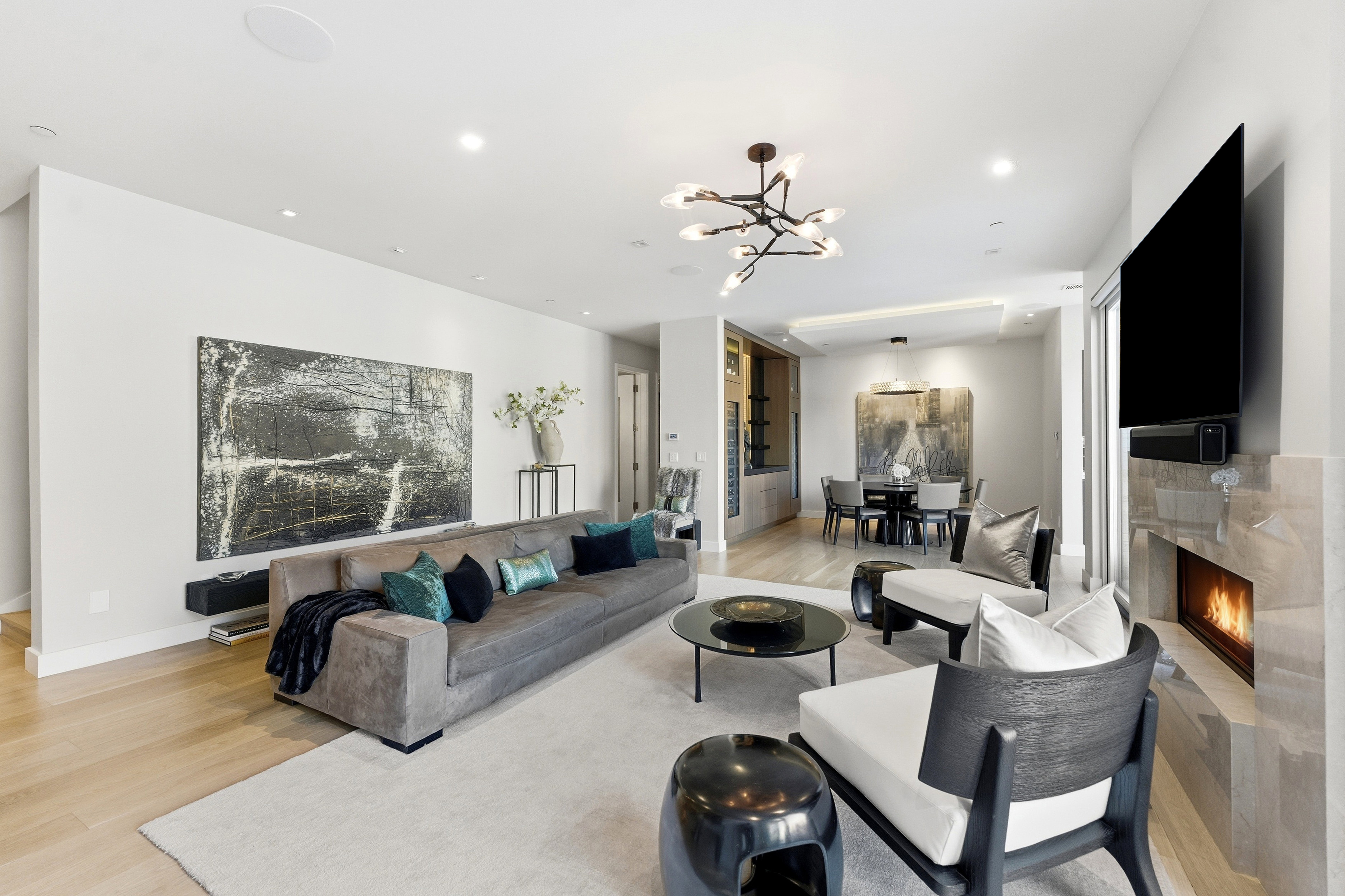 Open-concept living area featuring light wood-finish flooring, recessed lighting, and a modern chandelier