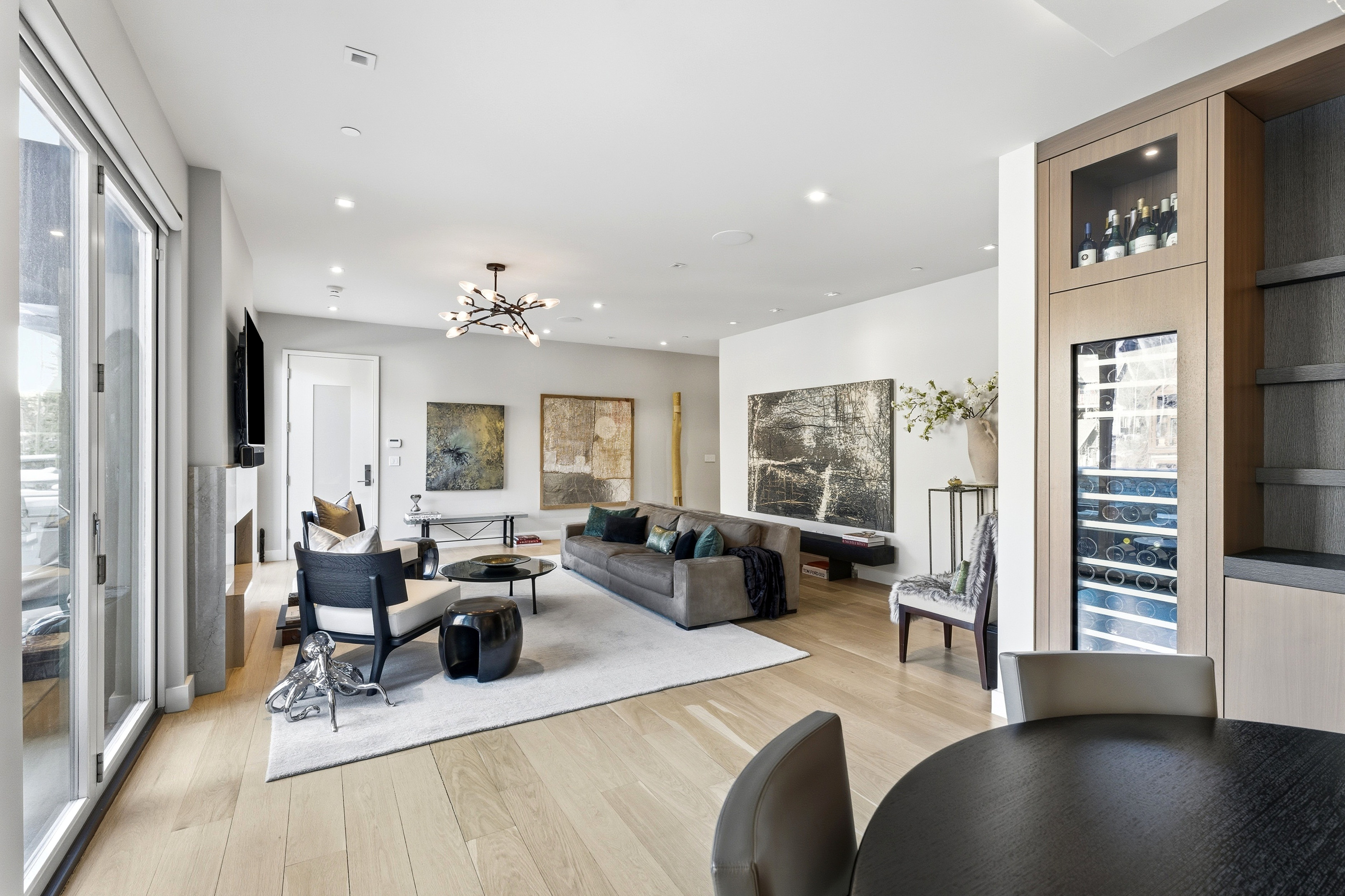 Spacious living area featuring light wood-finish flooring, recessed lighting, and a modern chandelier