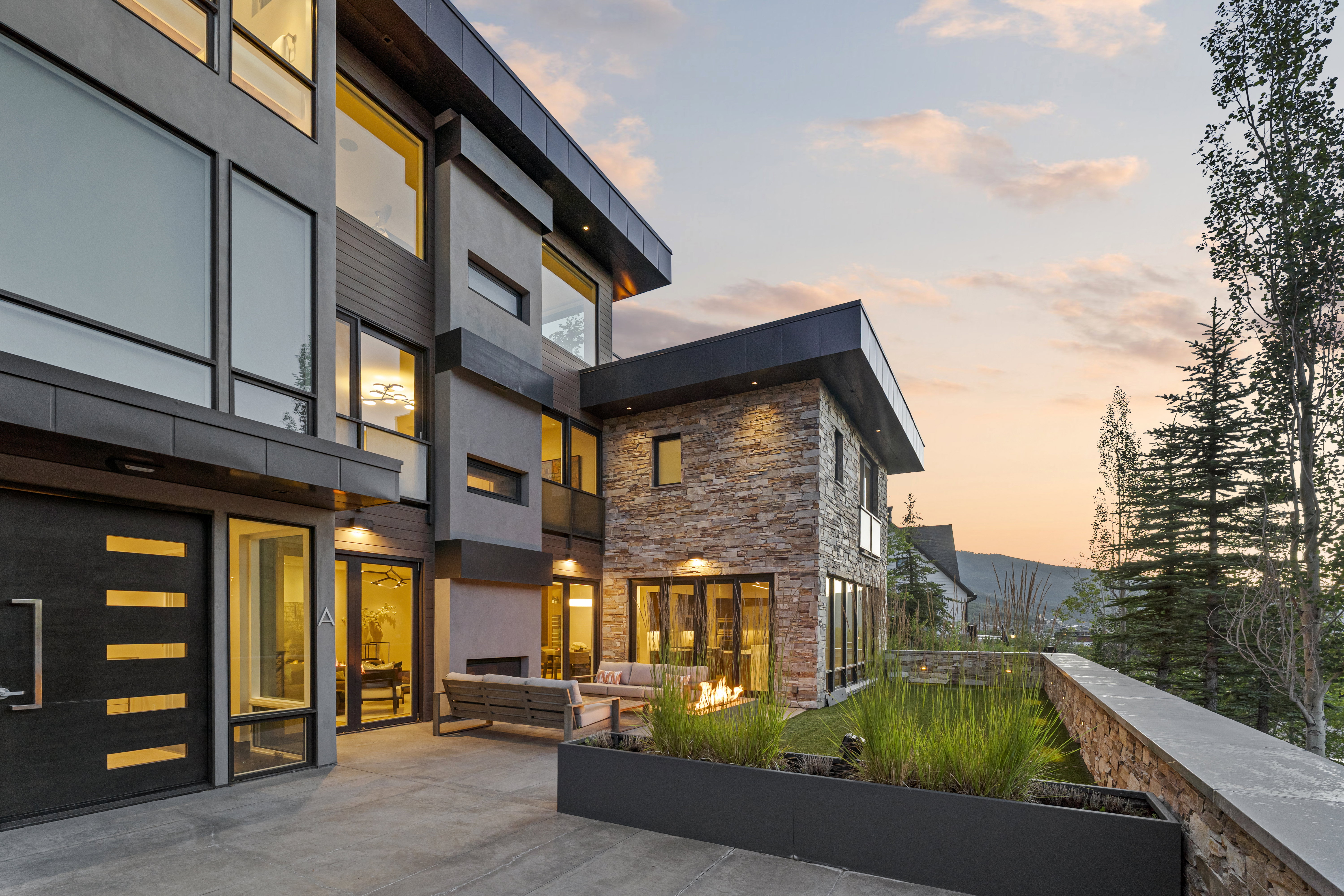 Modern architectural exterior featuring extensive window lines, stone and stucco finishes, and a contemporary entry door