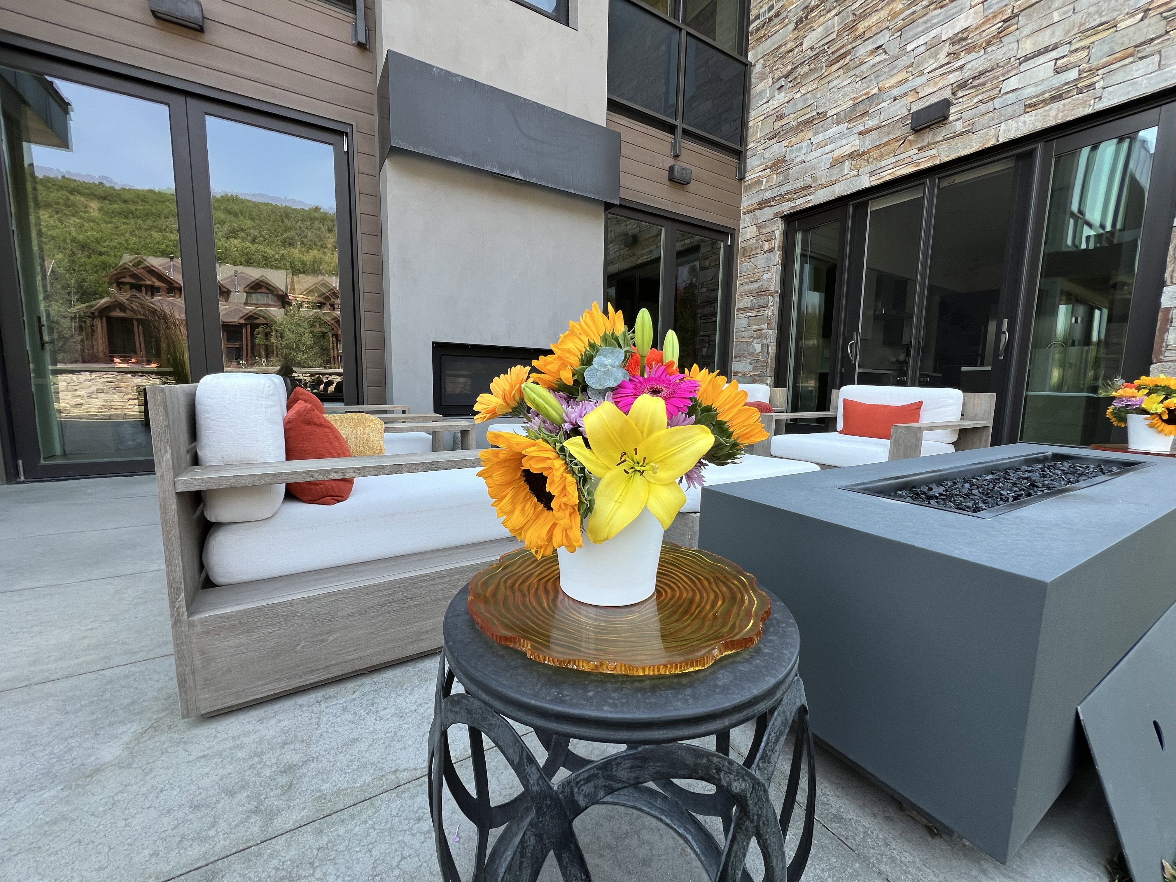 Expansive patio featuring a built-in fire pit, stone accent wall, and multiple floor-to-ceiling glass doors