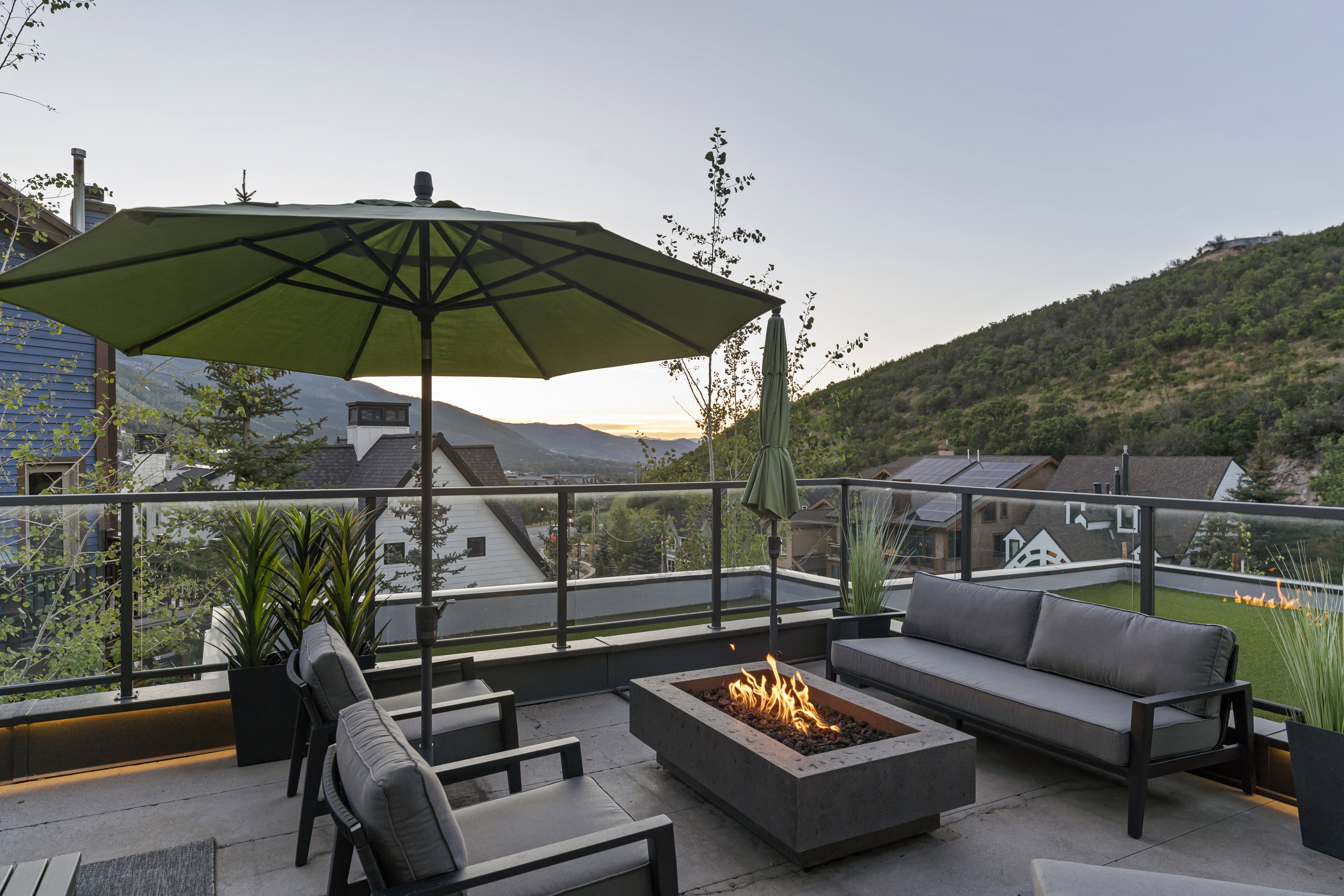Expansive outdoor patio featuring a built-in fire pit, glass panel railing, and integrated planters