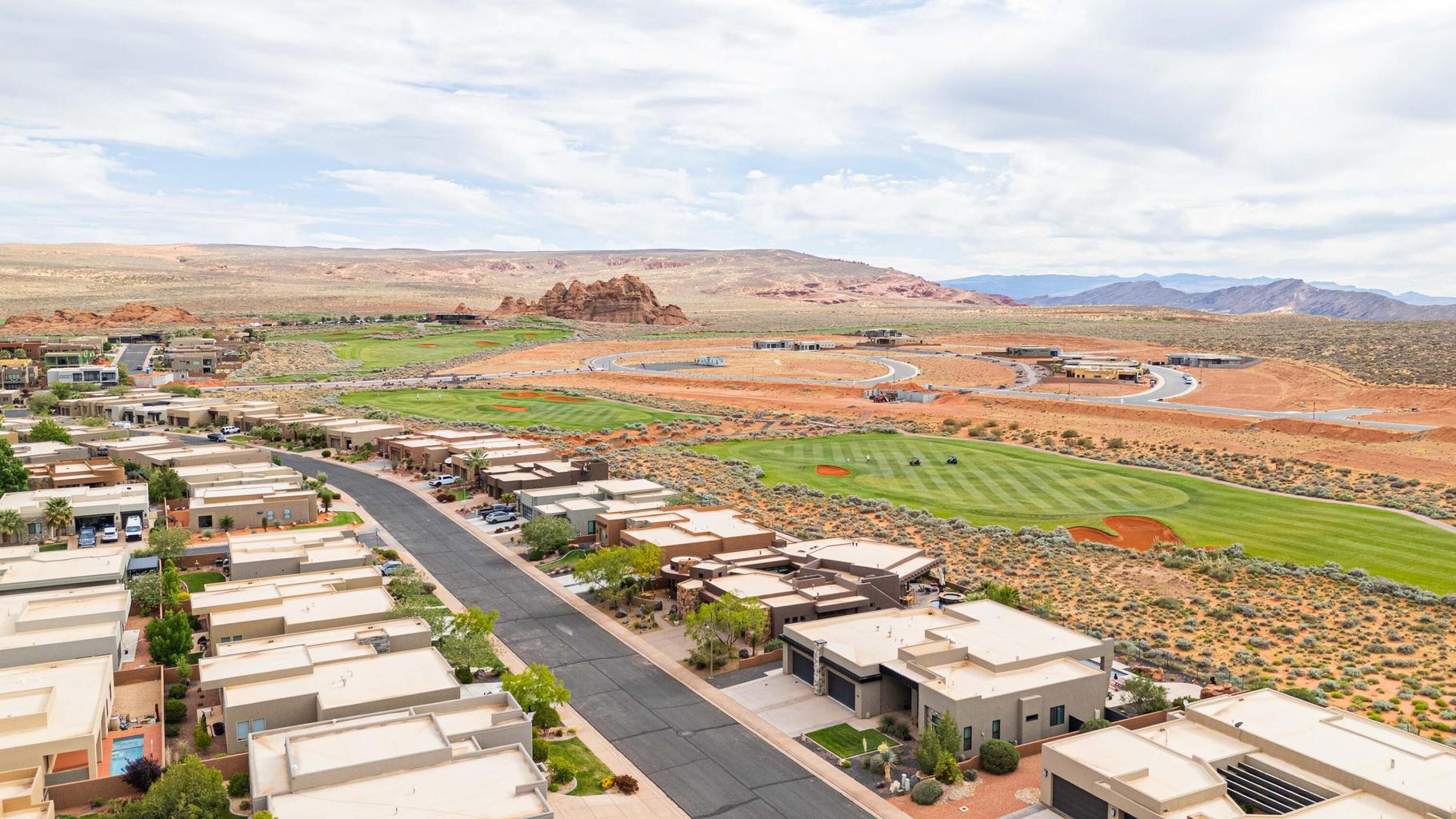 Modern desert community featuring a golf course, mountain backdrop, and contemporary flat-roof architecture