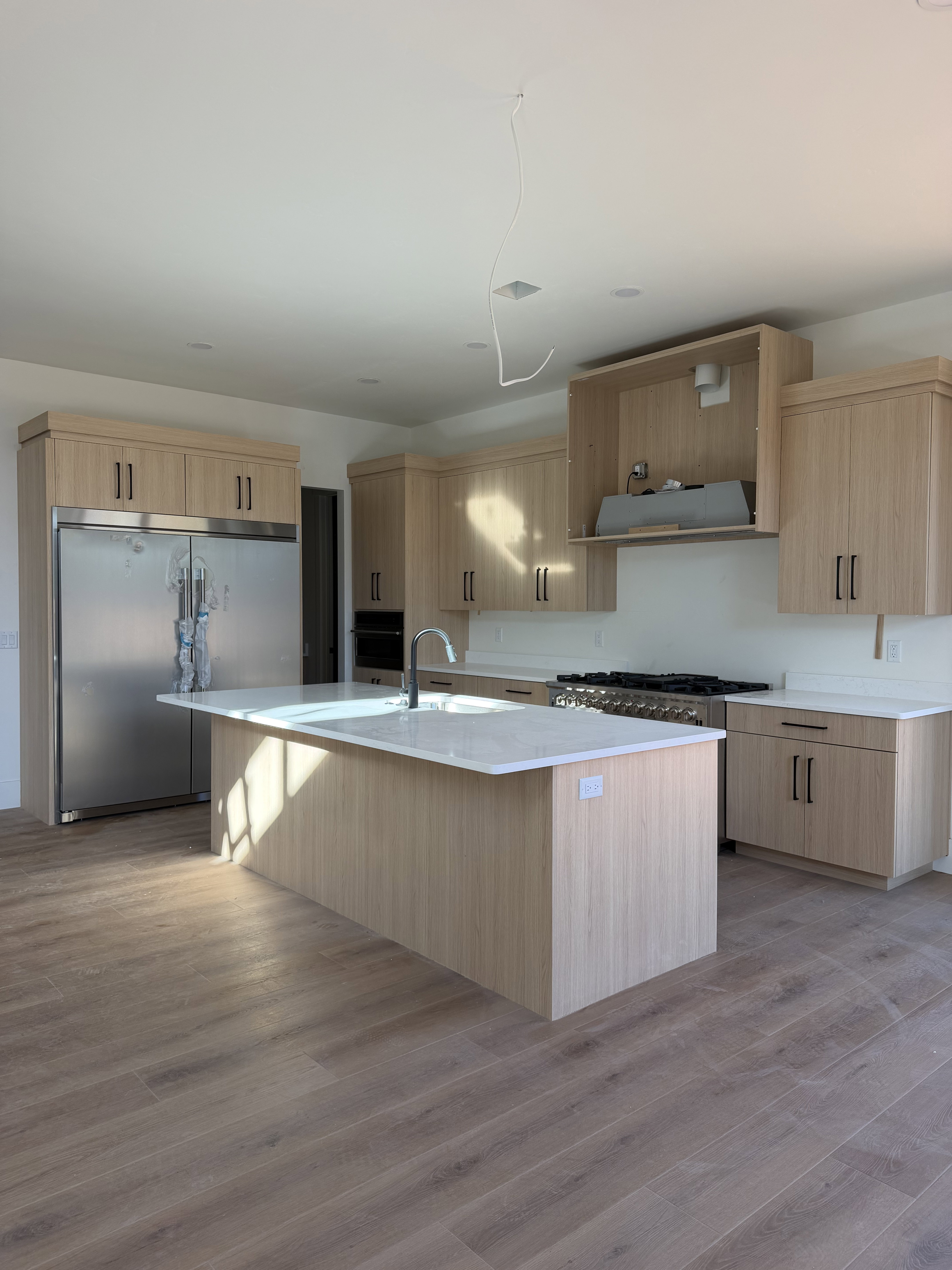 Modern kitchen featuring a spacious center island with a white countertop and undermount sink