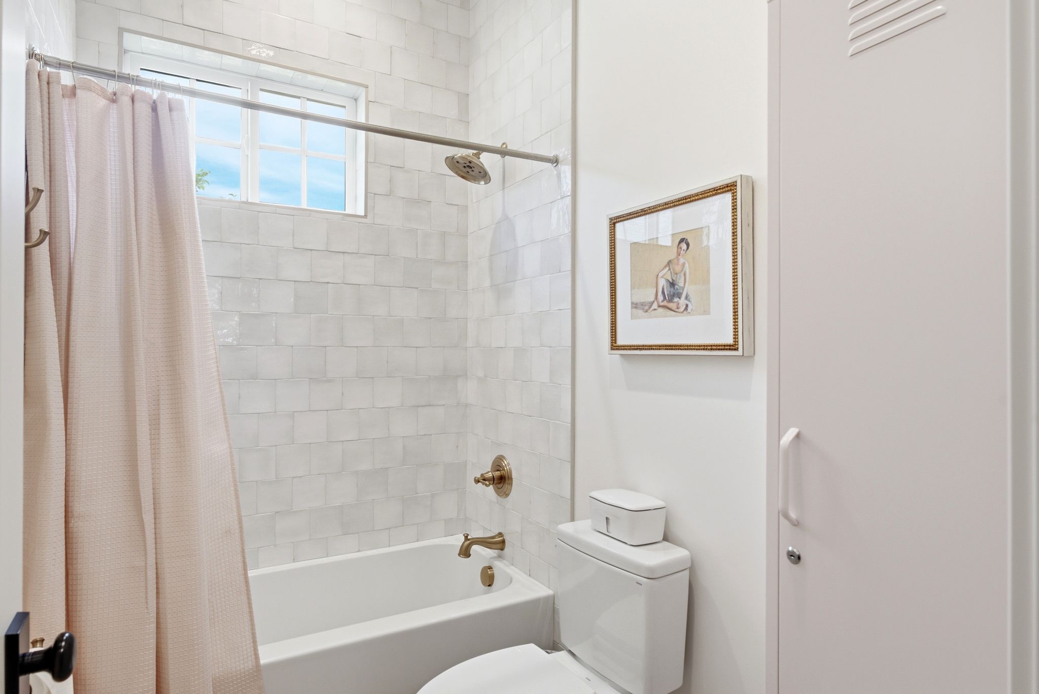 Bathroom featuring a white subway tile shower surround with a built-in tub, bronze fixtures, and an overhead window
