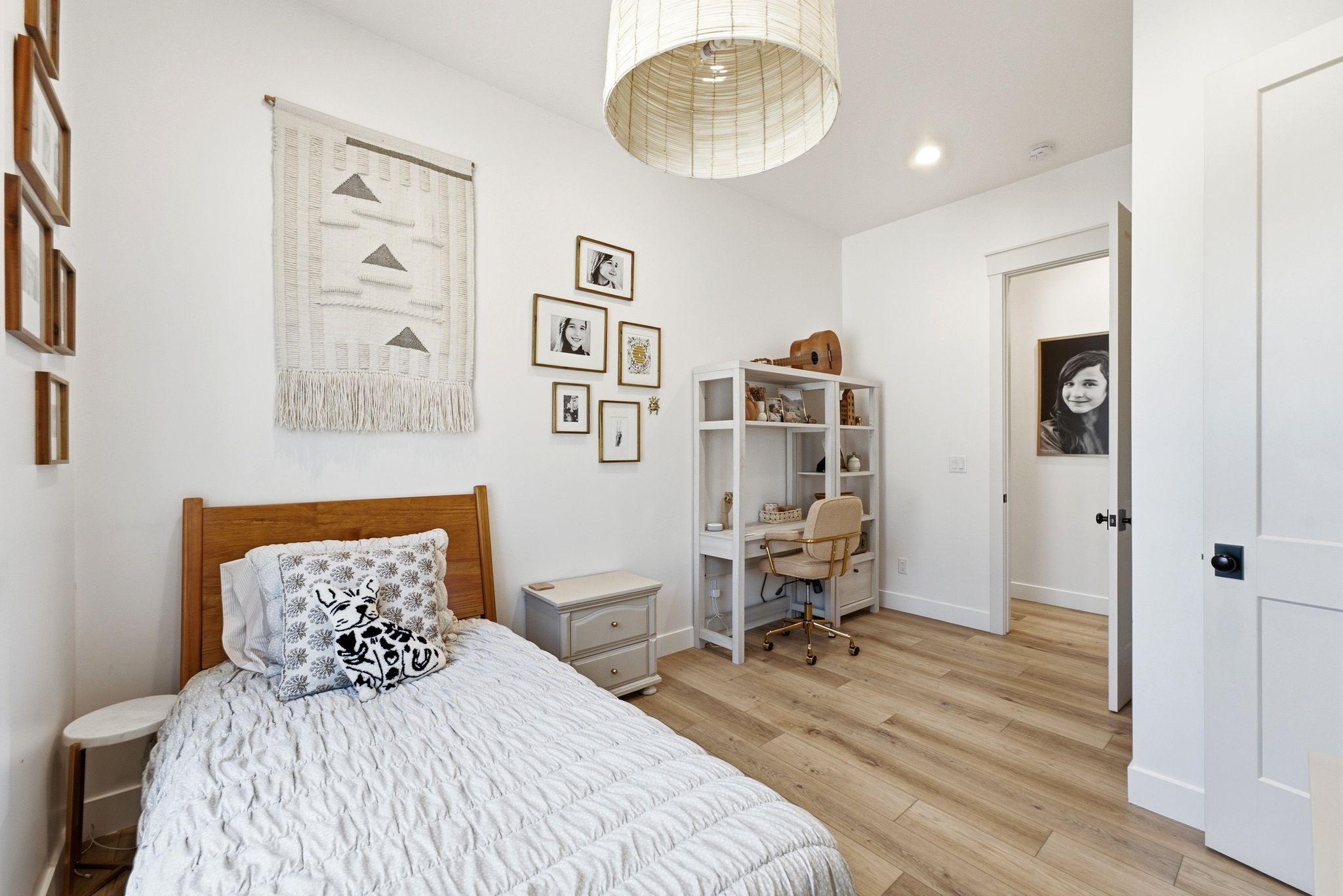 Interior room featuring light wood-finish flooring, white walls, and a white paneled door with black hardware