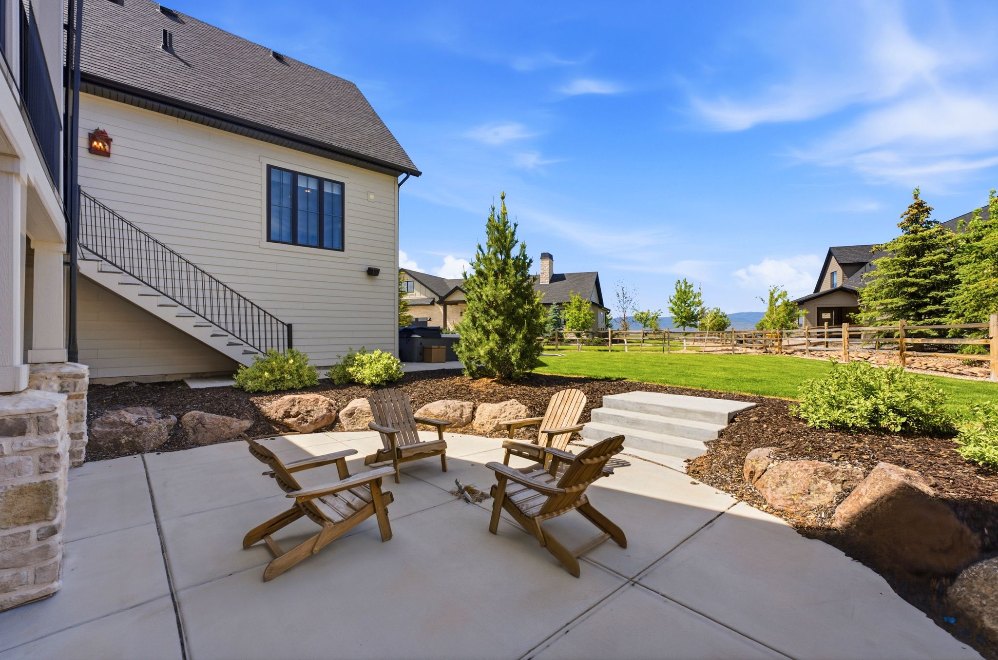 Outdoor patio with concrete surfacing, rock landscaping, and steps leading to a manicured lawn