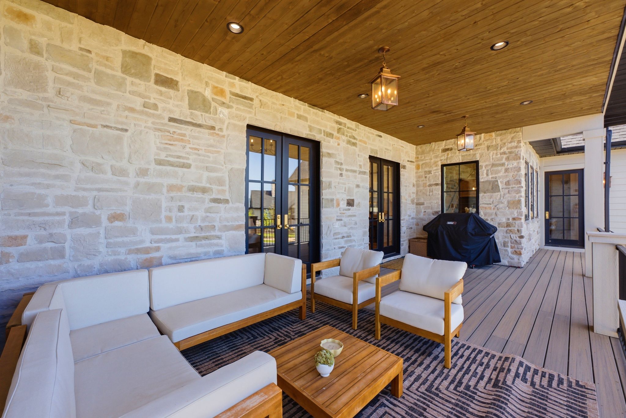 Covered outdoor patio featuring stone walls and a wood-paneled ceiling