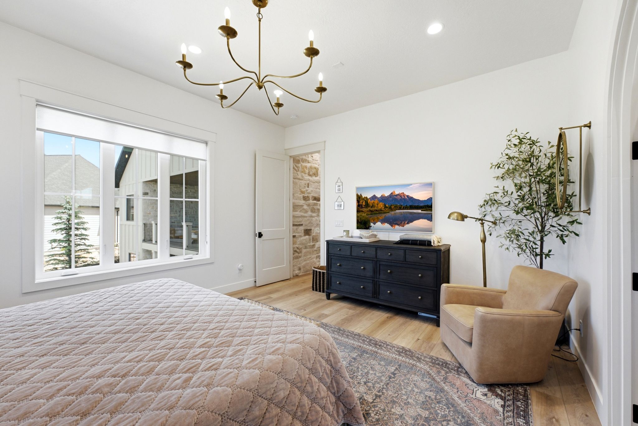 Bright room featuring a large window, light wood-finish flooring, a neutral wall color, and a multi-arm chandelier