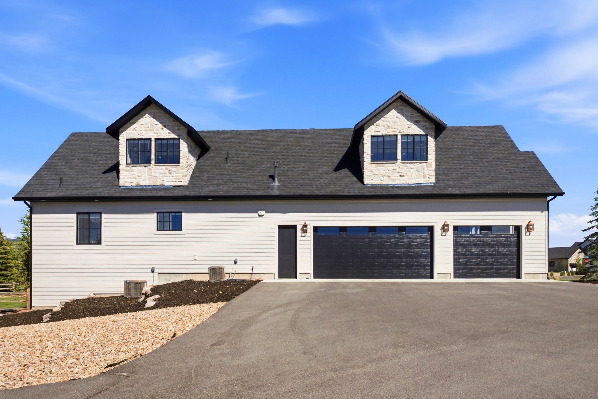 Three-car garage with contemporary black doors and exterior sconce lighting