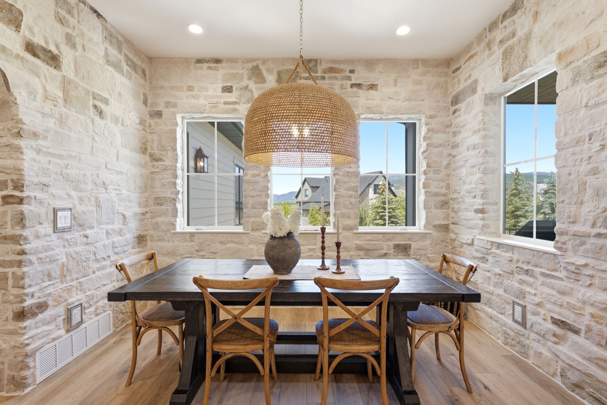 Stone-clad accent walls featuring multiple window openings, recessed lighting, and a prominent woven pendant light