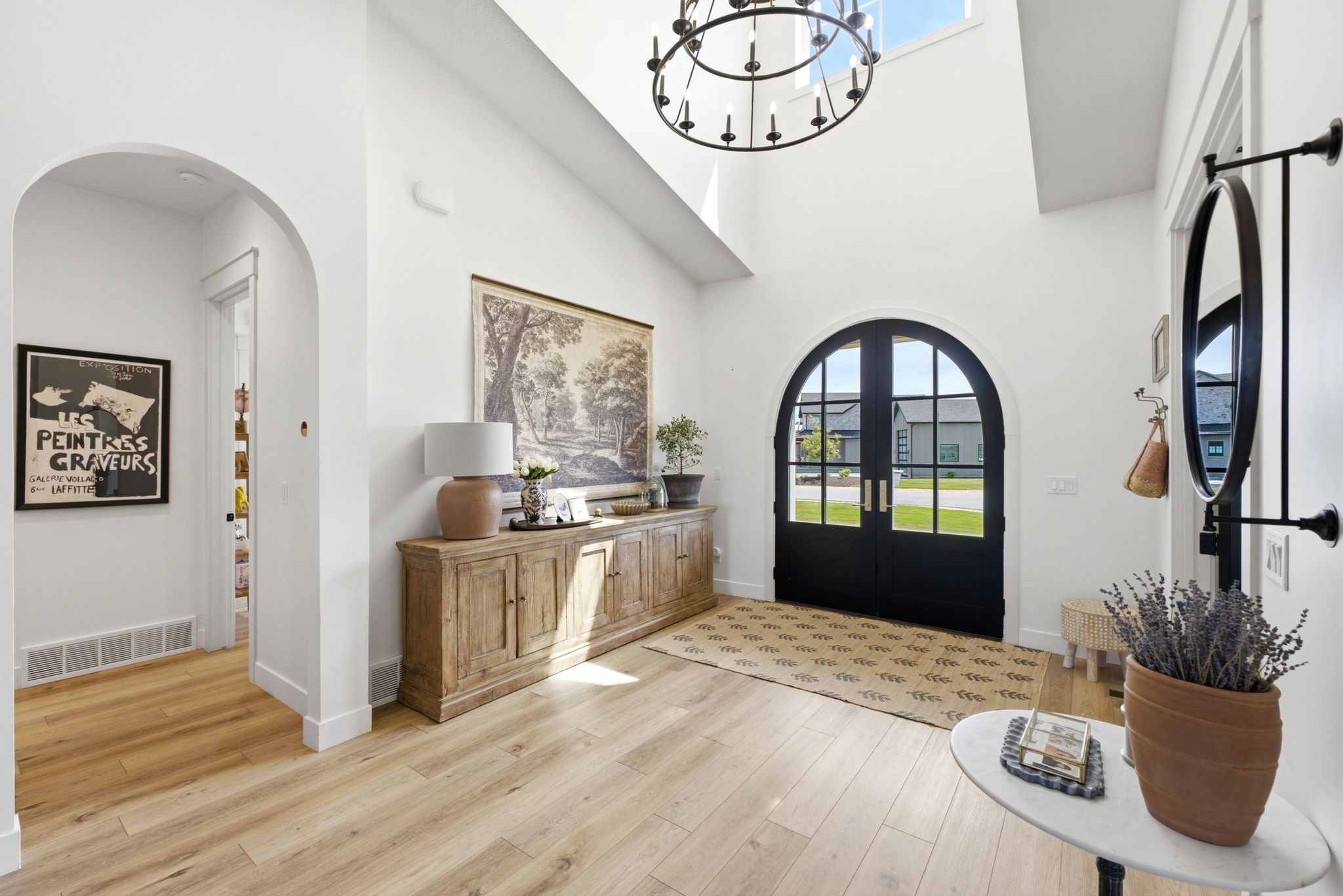 Grand entry featuring a tall arched double door, transom window, and a large chandelier