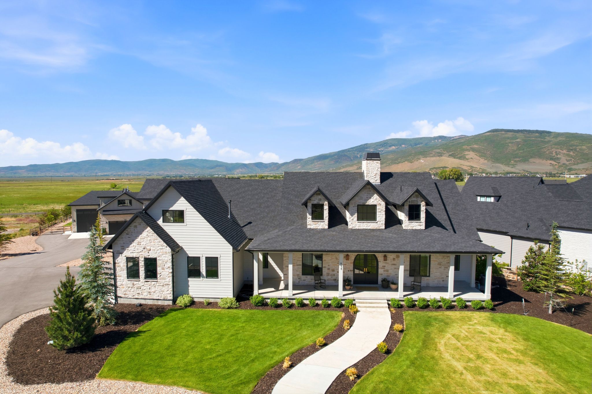 Stone and siding exterior with a large covered porch and dark-pitched roof