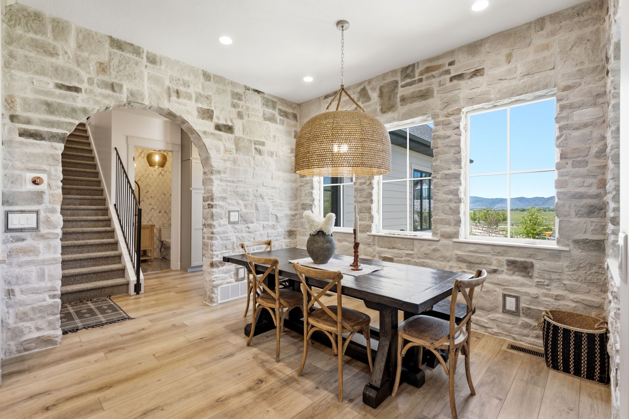 Stone accent wall with dual windows, wood-finish flooring, and arched entryway