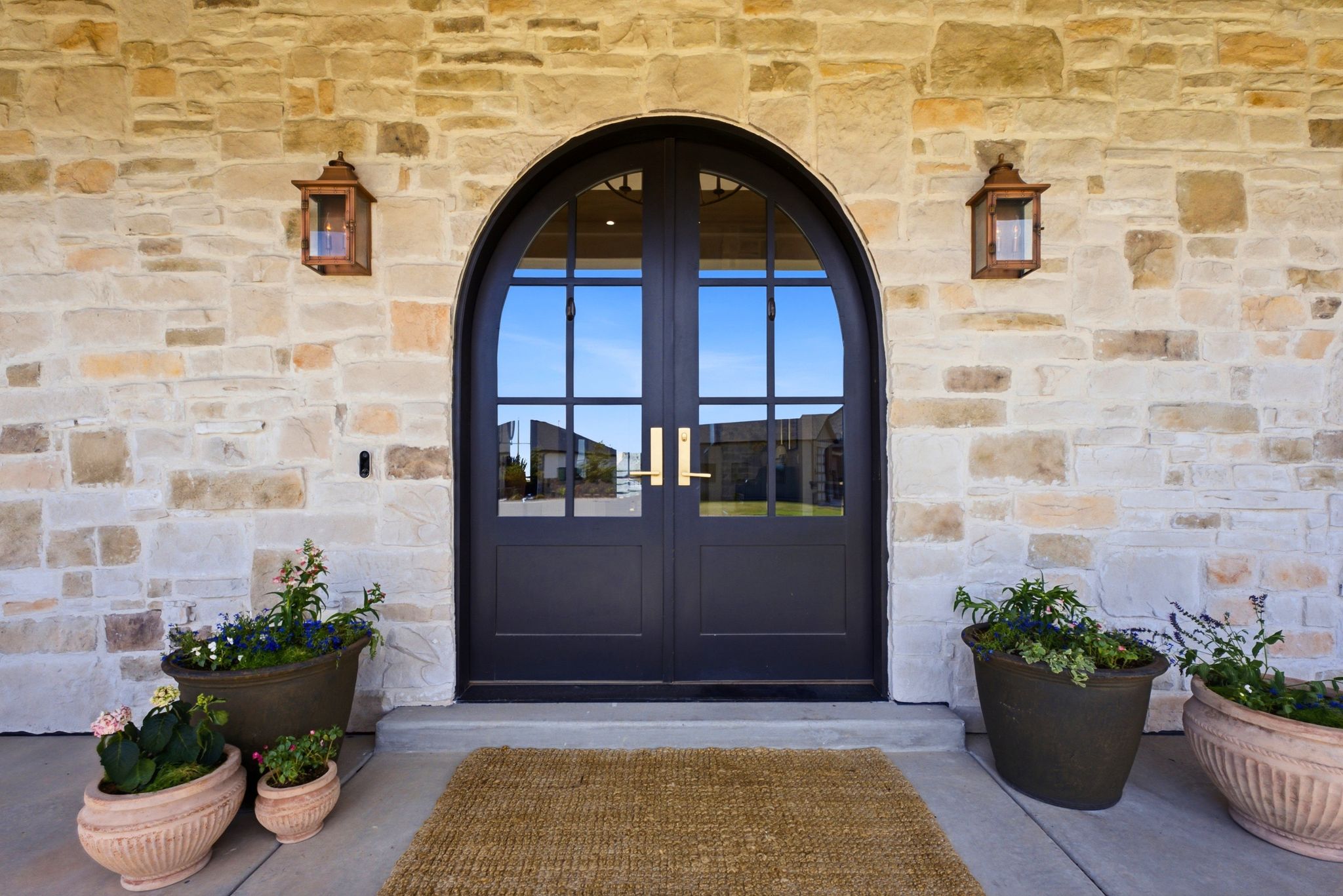 Arched double entry doors with gold-toned hardware, set within a stone facade