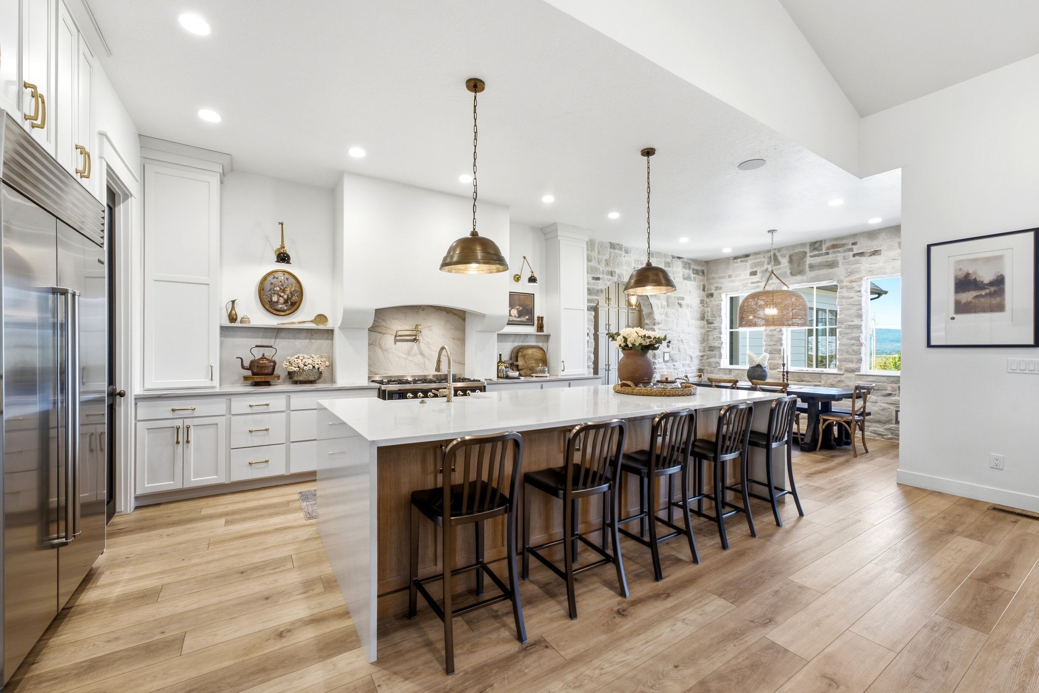 Gourmet kitchen featuring a large central island with seating, stainless steel appliances, and white cabinetry