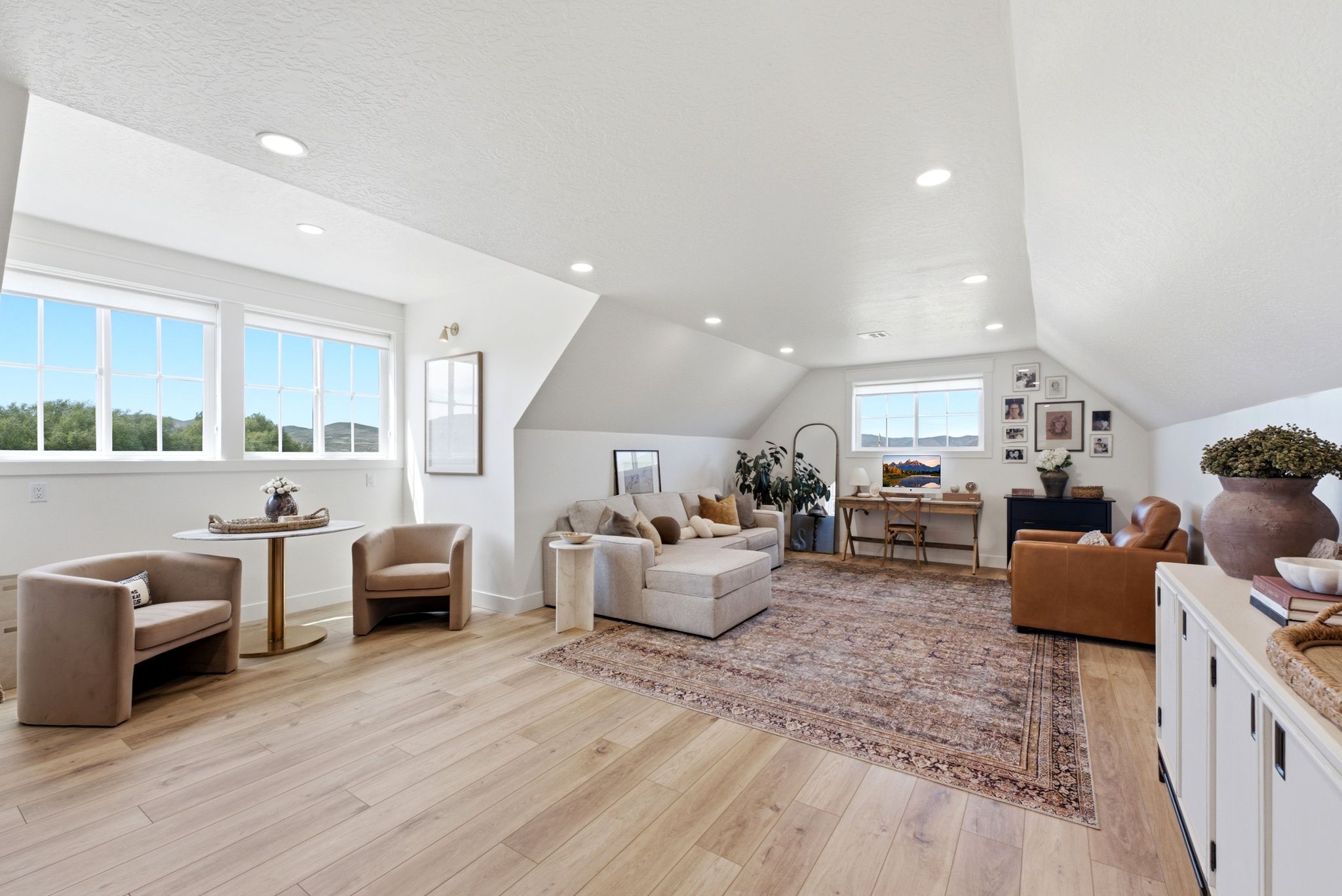 Spacious room featuring light wood-finish flooring, recessed lighting, and multiple windows