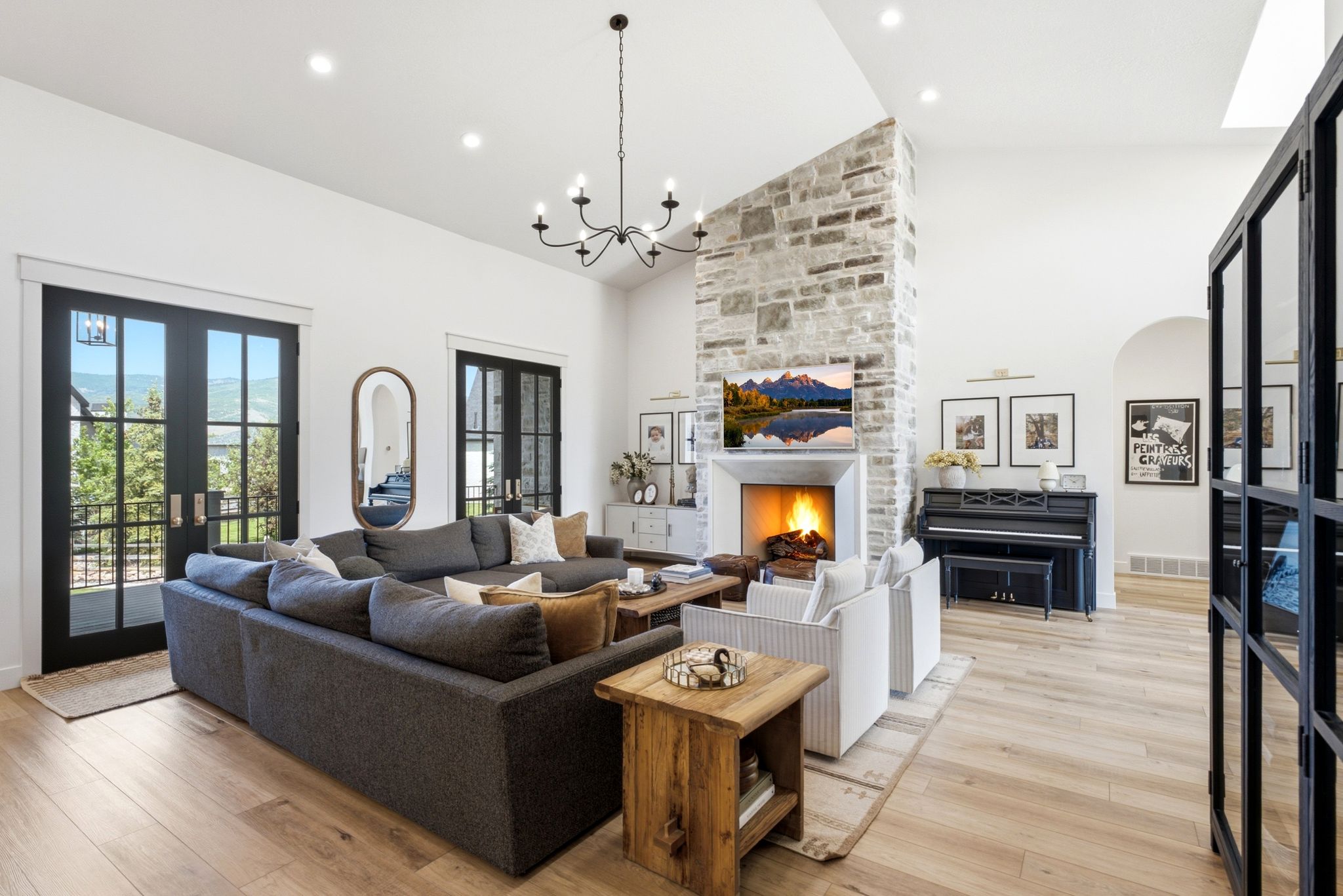 Spacious living area featuring a stone fireplace with a substantial mantel, vaulted ceilings, and recessed lighting