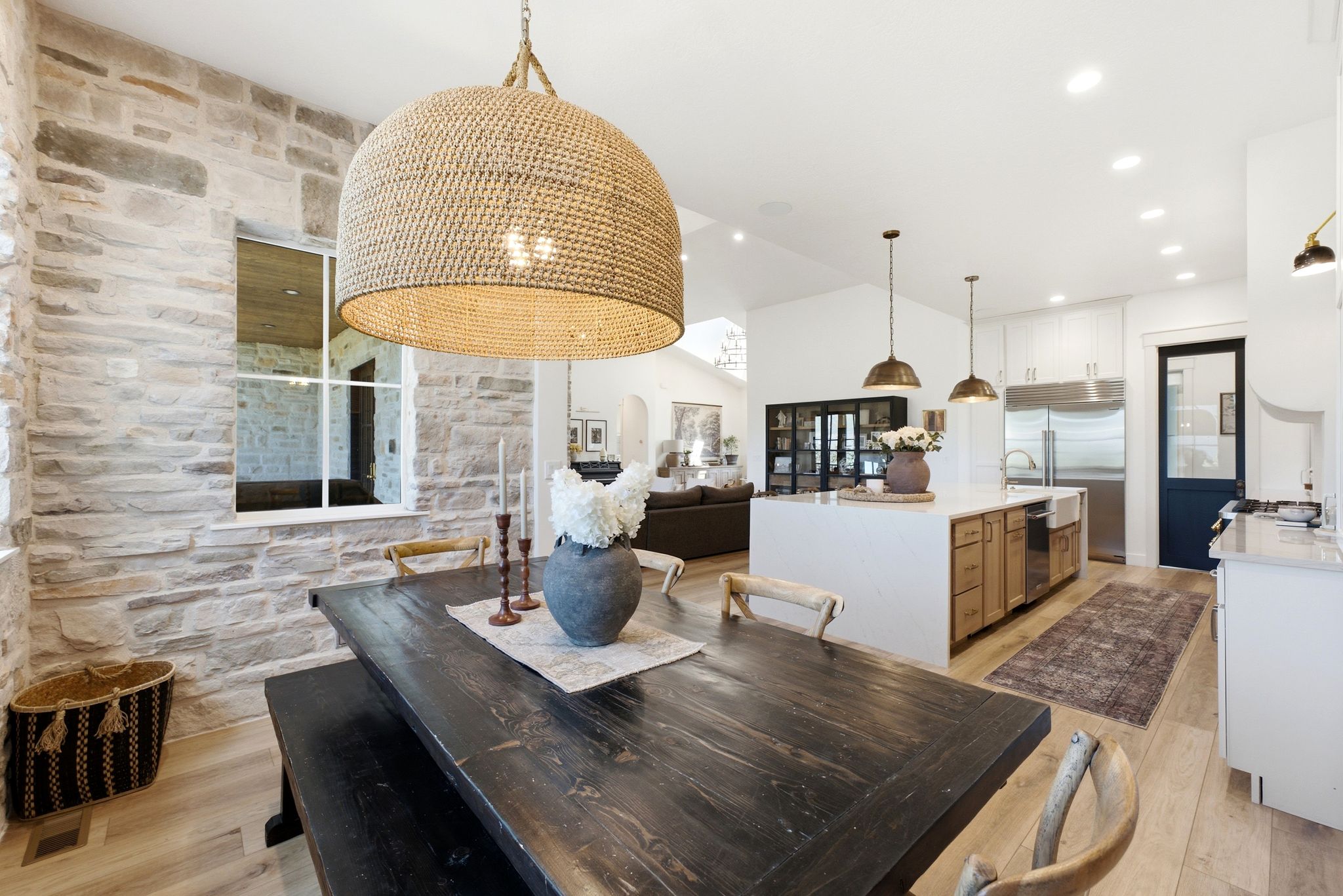 Dining area featuring a woven pendant light and stone accent wall
