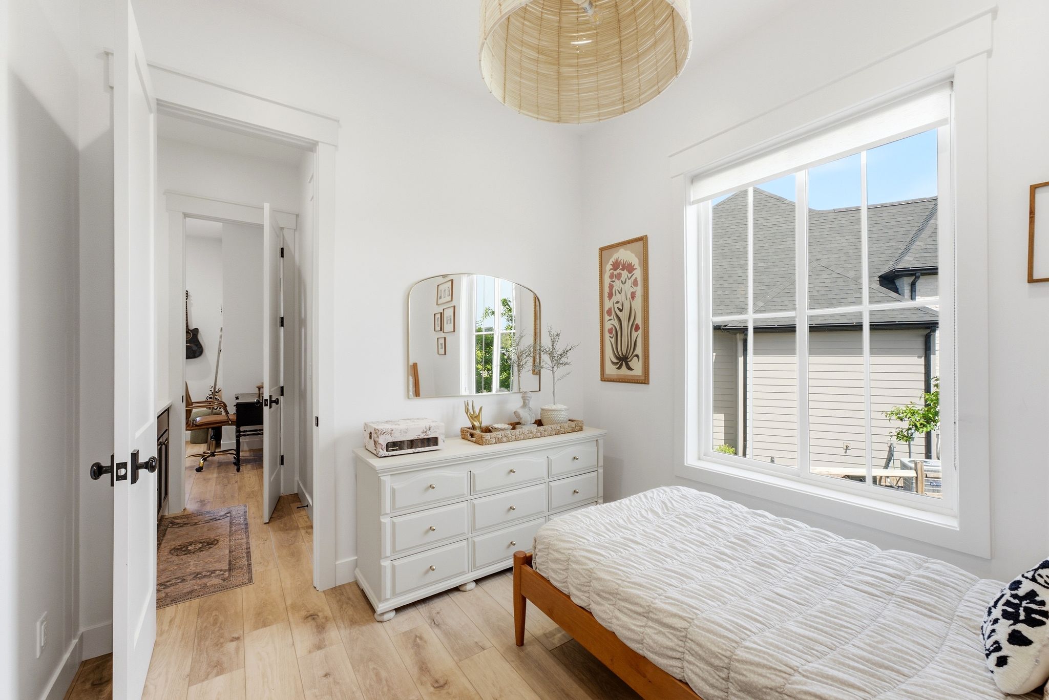Bright room with light wood-finish flooring, a large window featuring white grids, and crisp white trimwork