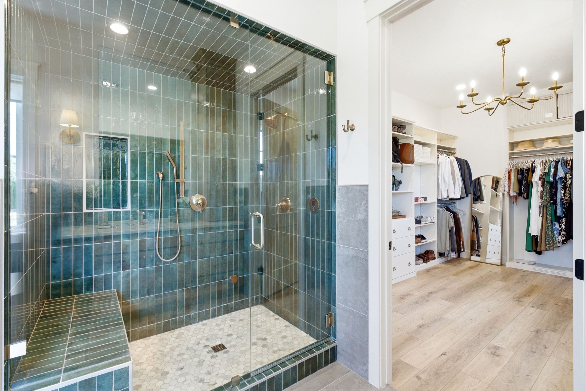 Spacious walk-in shower with a glass enclosure, vertical teal subway tile, a built-in bench, and a hexagonal mosaic tile floor