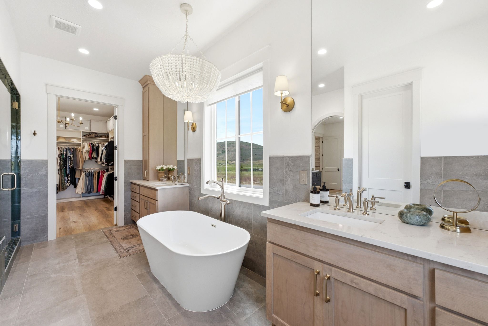 Spacious bathroom featuring a freestanding soaking tub, a walk-in shower with a glass enclosure, and a double vanity with an undermount sink and light-toned cabinetry