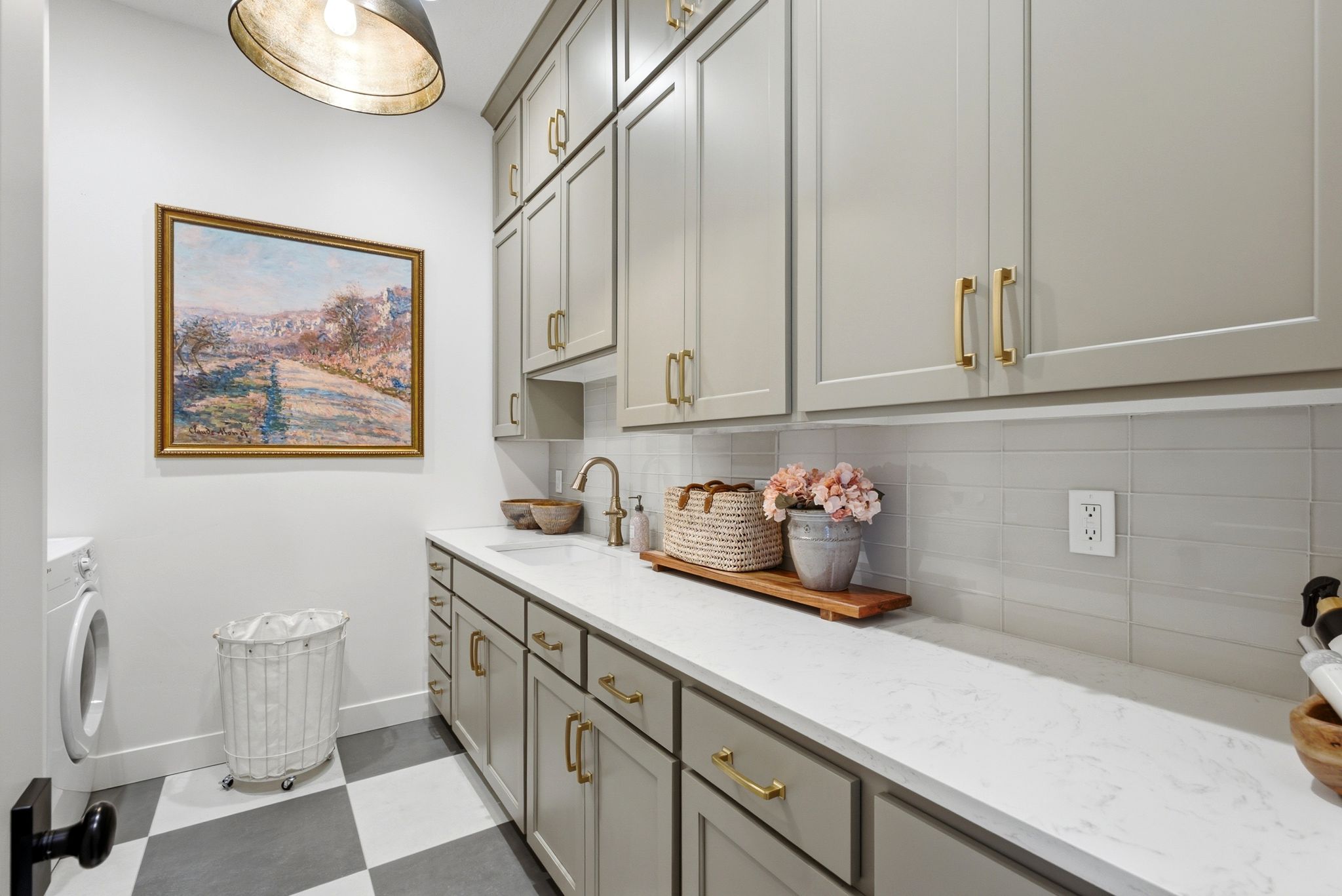 Utility room featuring a built-in sink, extensive cabinetry with gold-tone hardware, a white countertop, and checkered floor tiling