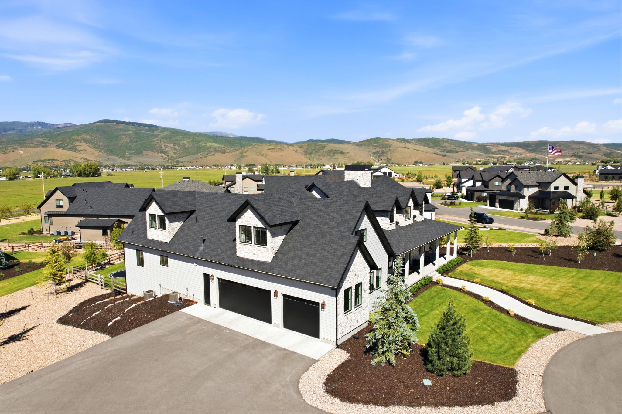 Modern farmhouse-style residence with a dark asphalt shingle roof and light-toned siding