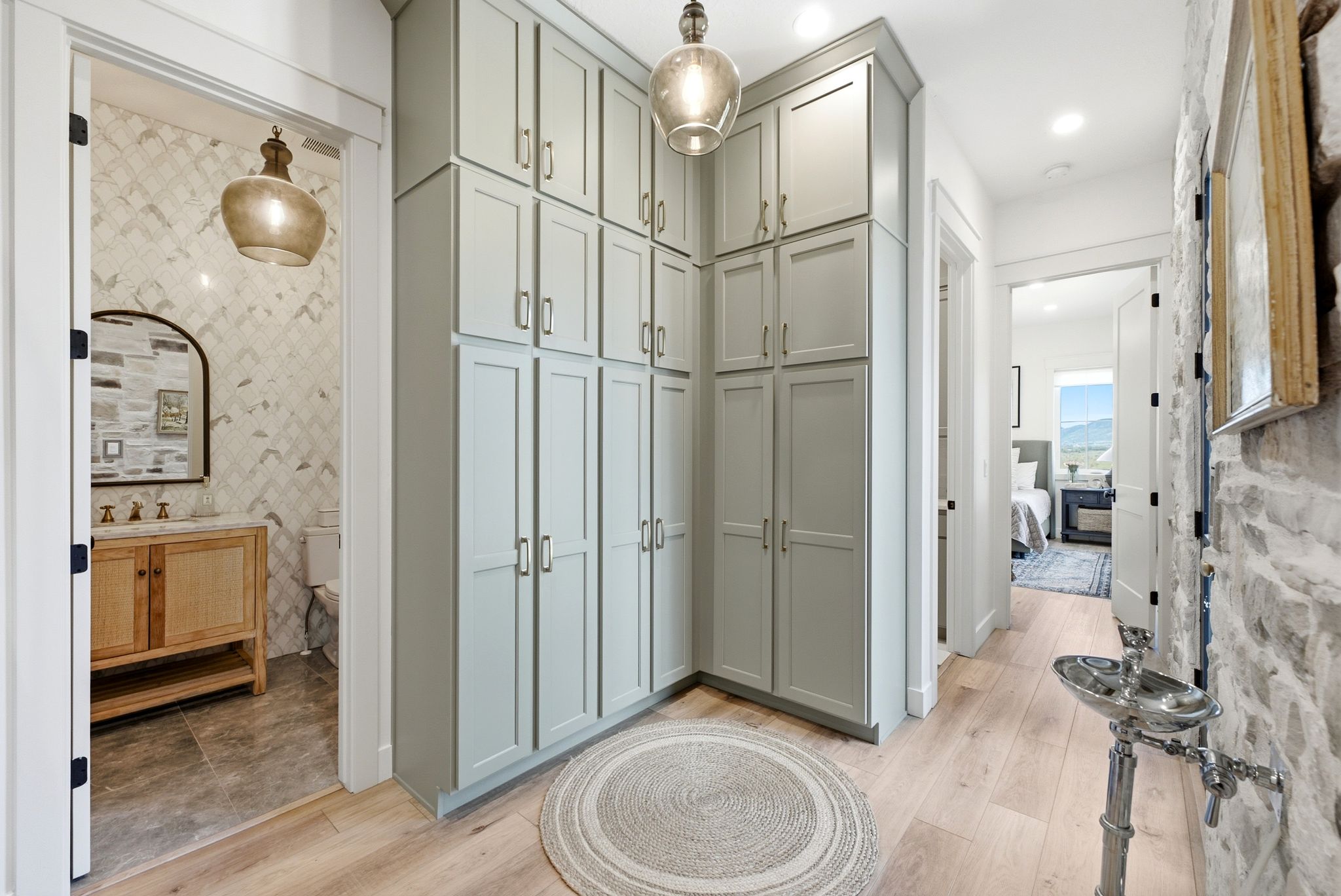 Built-in cabinetry with ample storage, light wood-finish flooring, stone accent wall, recessed lighting, and a prominent pendant light fixture
