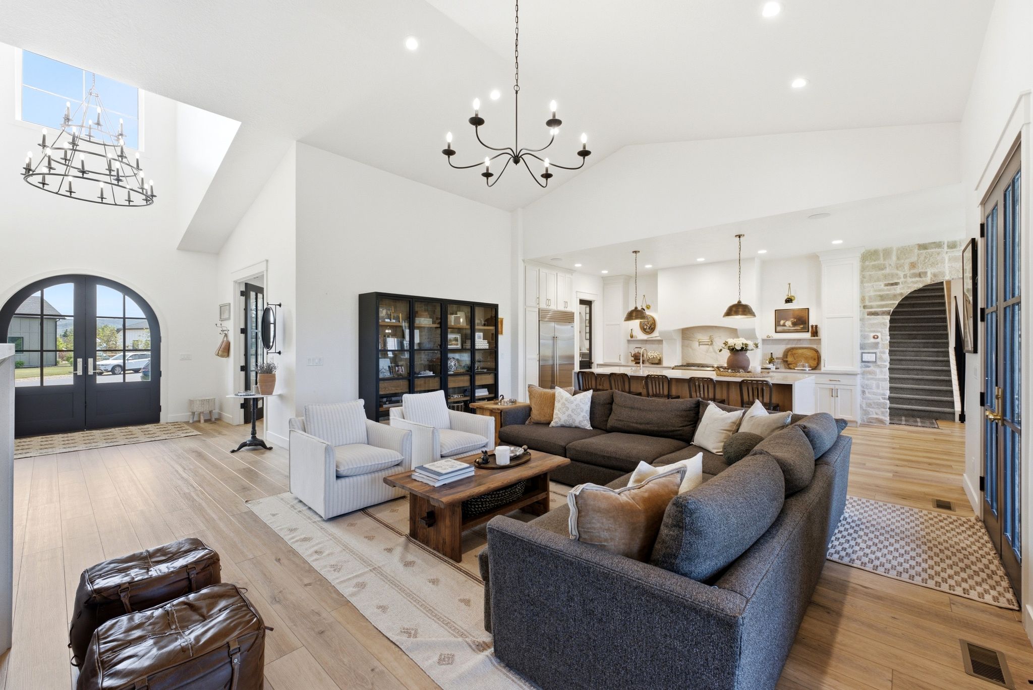 Expansive open-concept living area featuring high vaulted ceilings, light wood-finish flooring, and recessed lighting