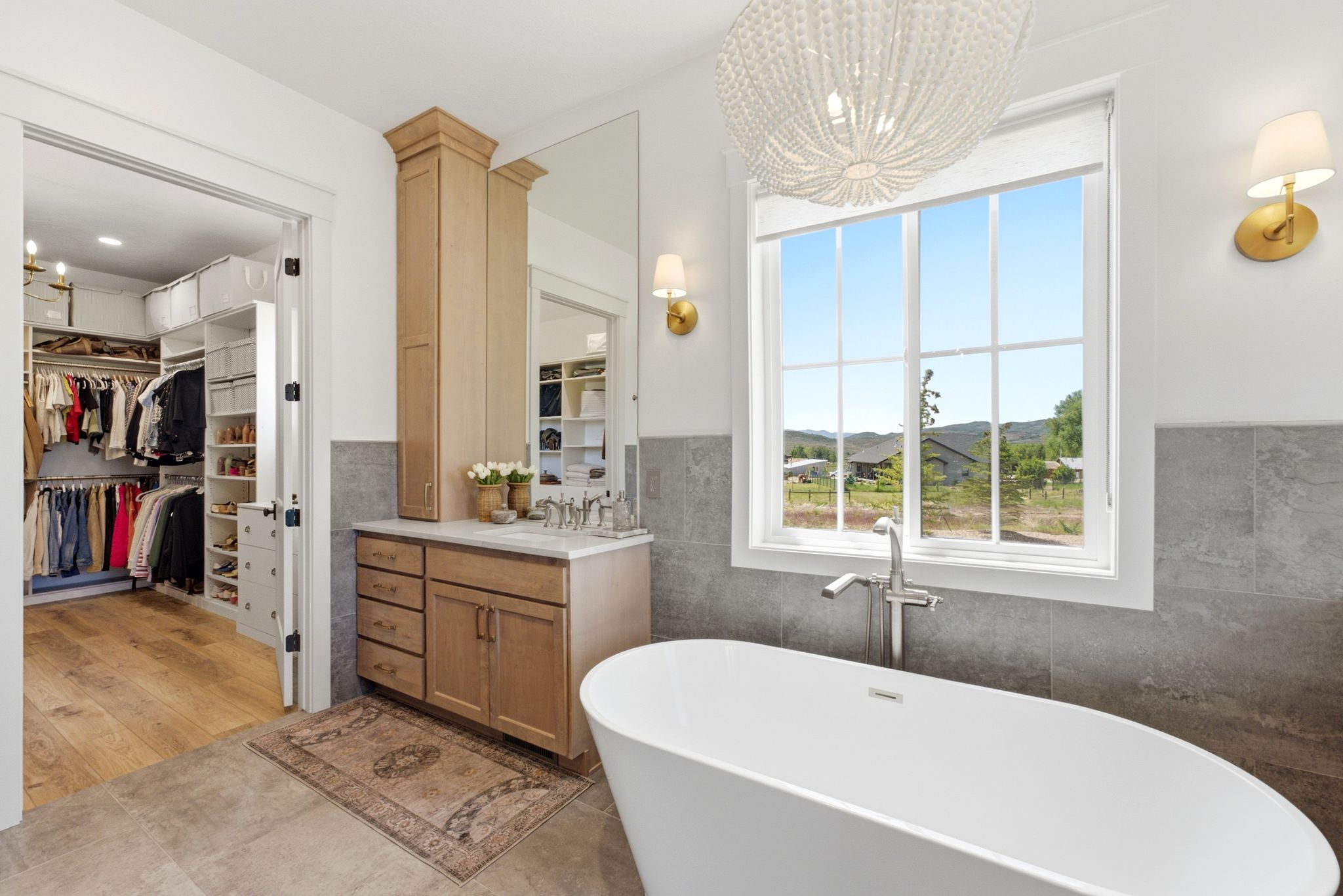 Bathroom featuring a freestanding soaking tub, single vanity with wood-finish cabinetry, and a walk-in closet with built-in organization systems