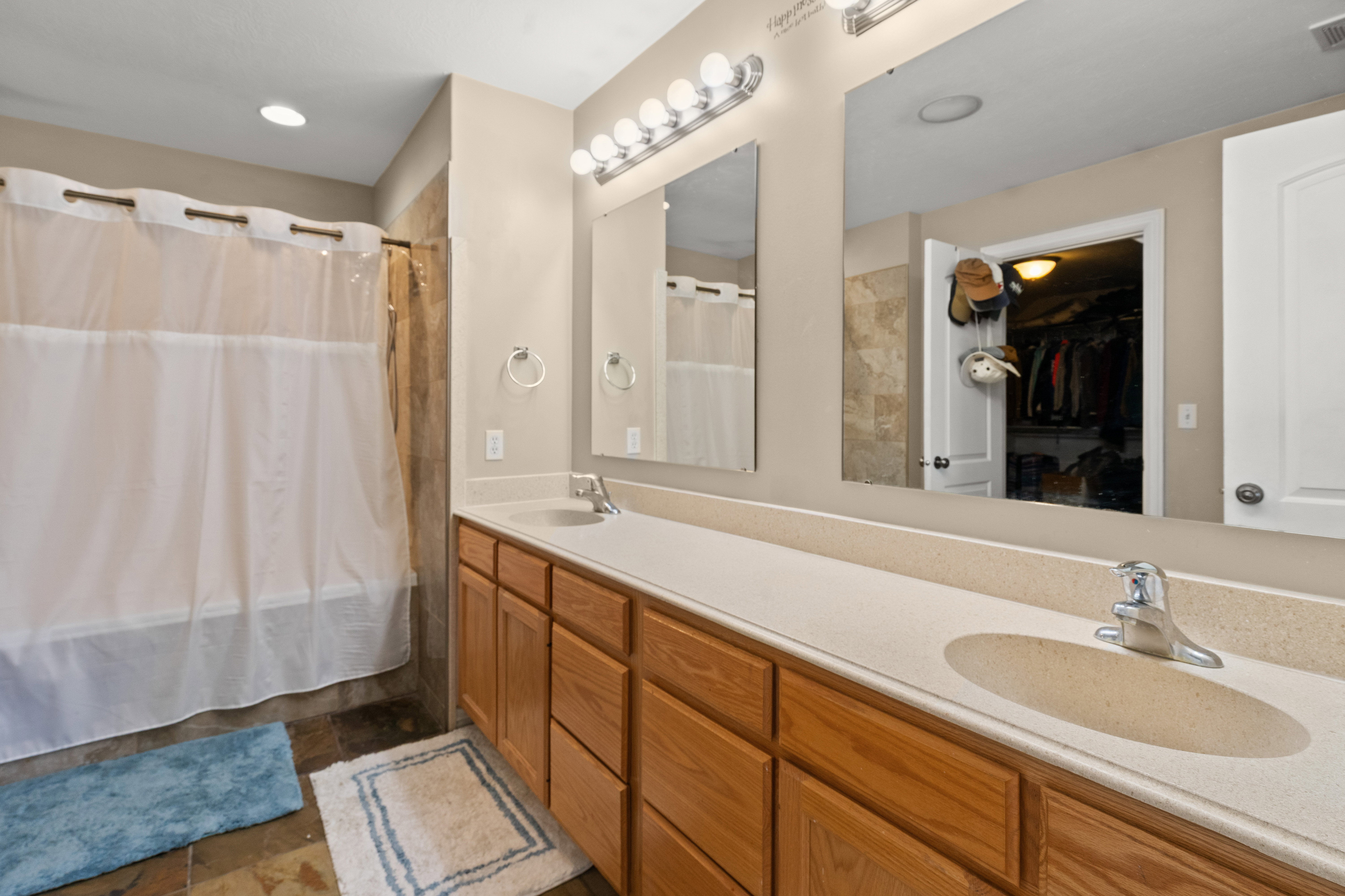 Bathroom featuring a dual vanity with a light-toned countertop, wood-finish cabinetry, and individual sinks