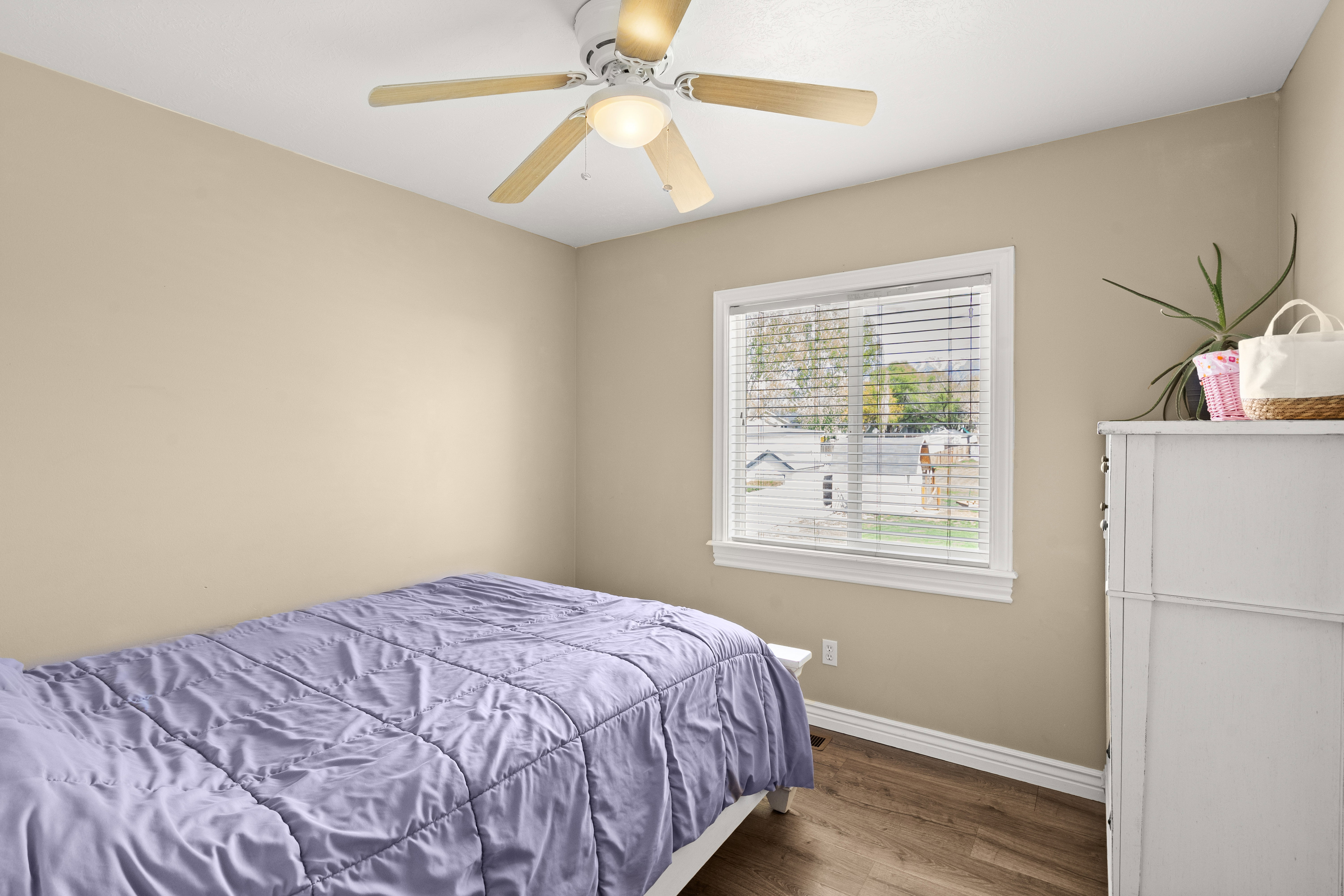Bright room featuring a window with horizontal blinds, wood-finish flooring, a ceiling fan with light, and light-toned walls