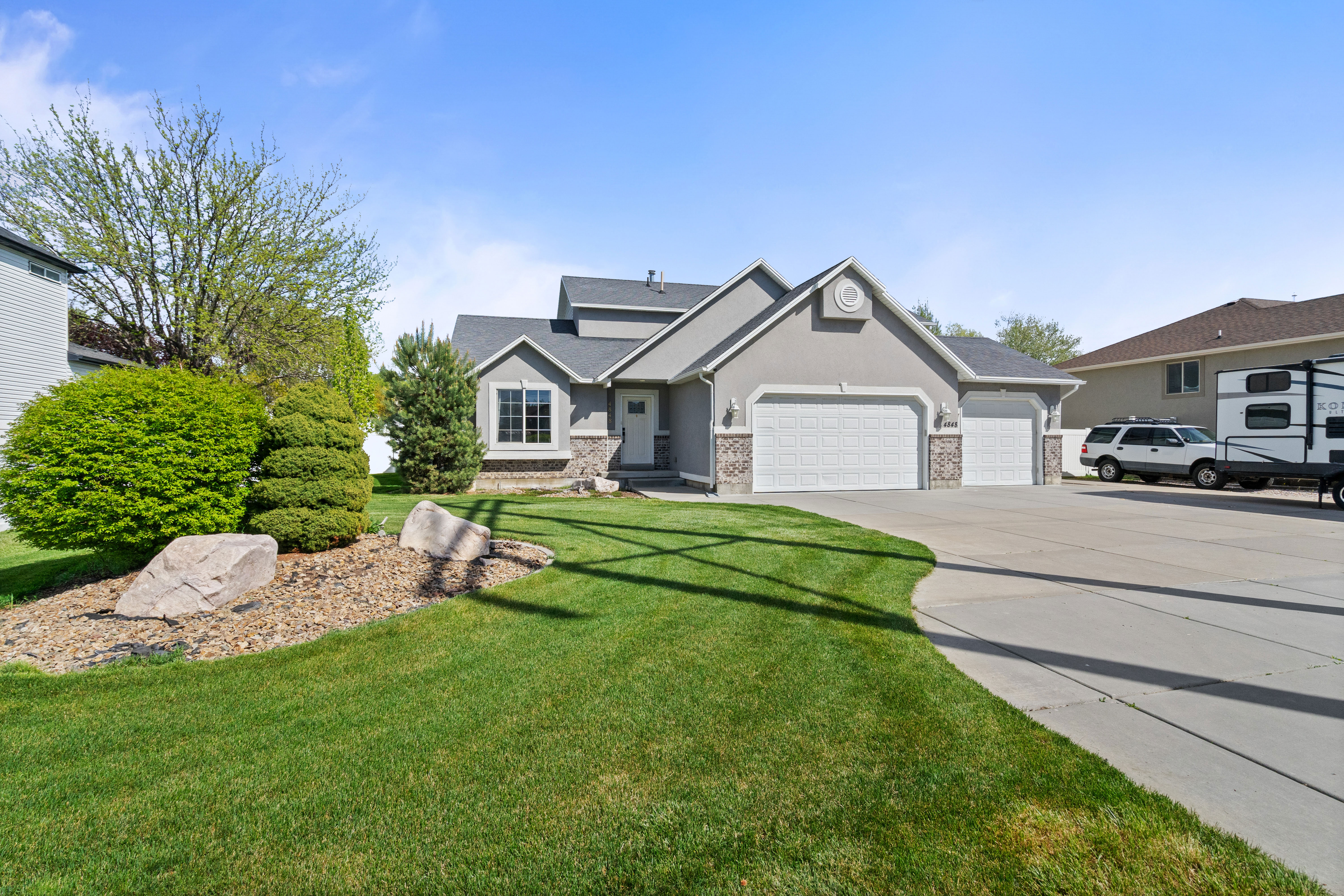 Gray stucco exterior with stone accents and a multi-car garage
