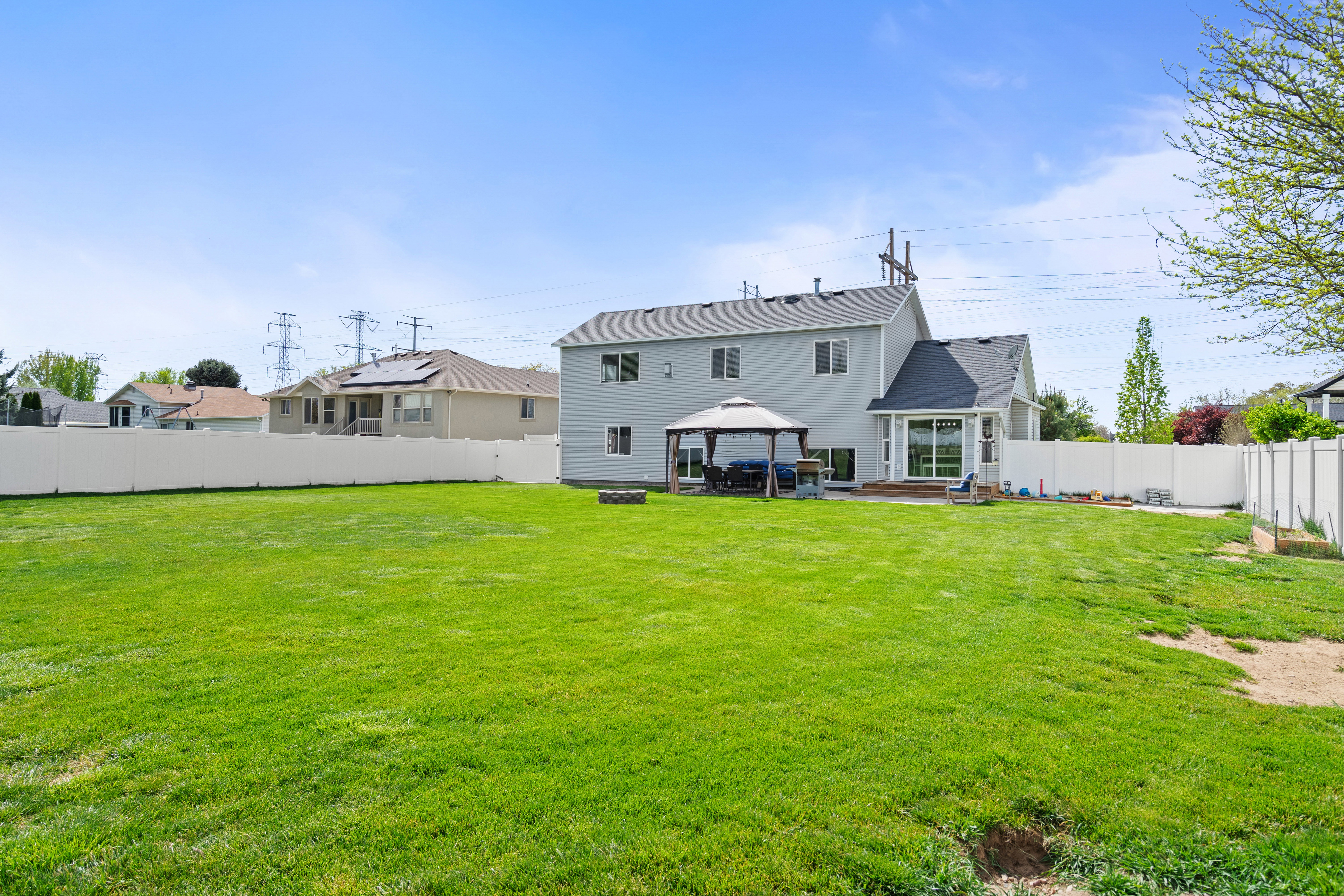 Expansive backyard with a manicured lawn, full fencing, and a built-in fire pit area