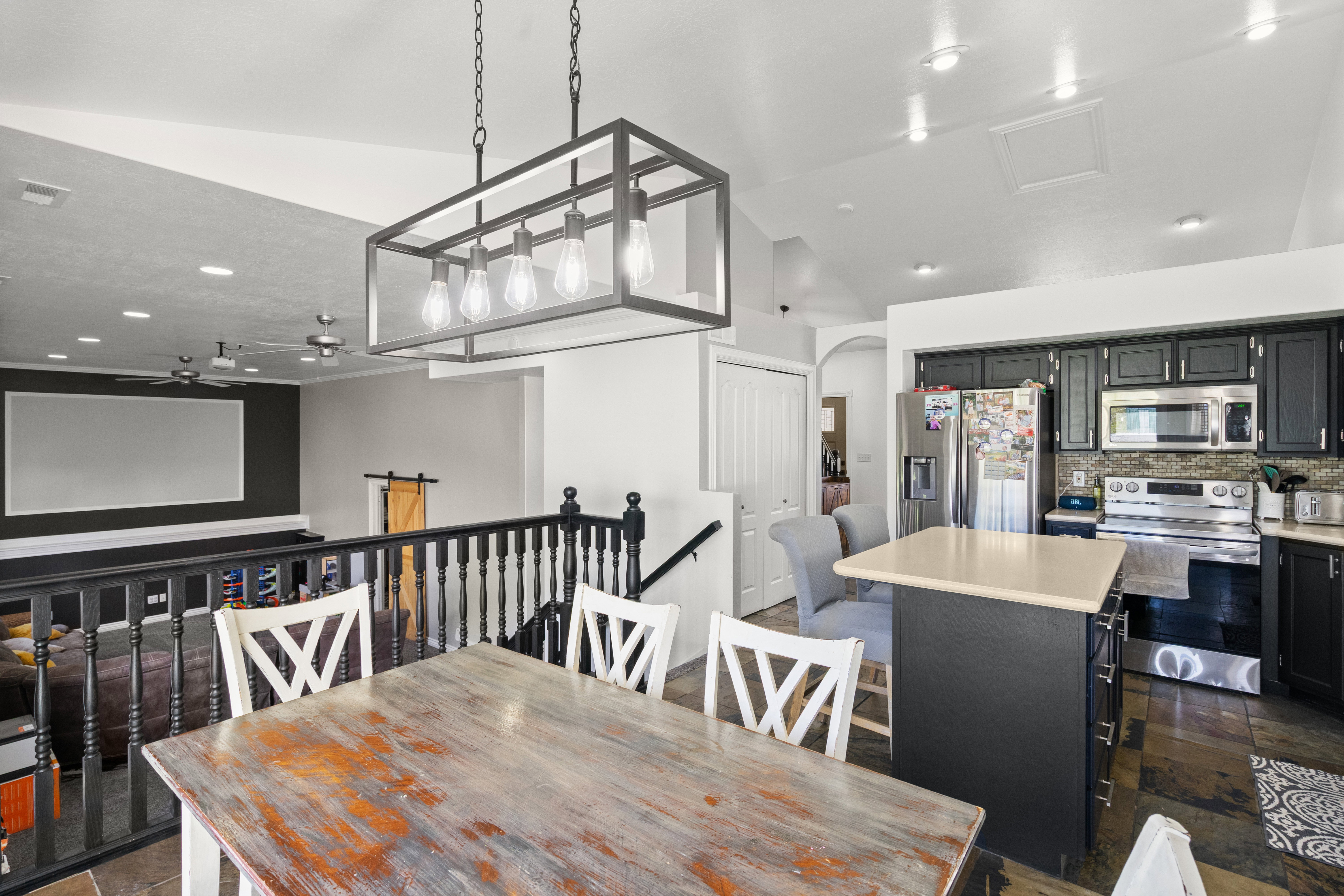 Kitchen and dining area featuring dark cabinetry, stainless steel appliances, and a central island with a light-colored countertop