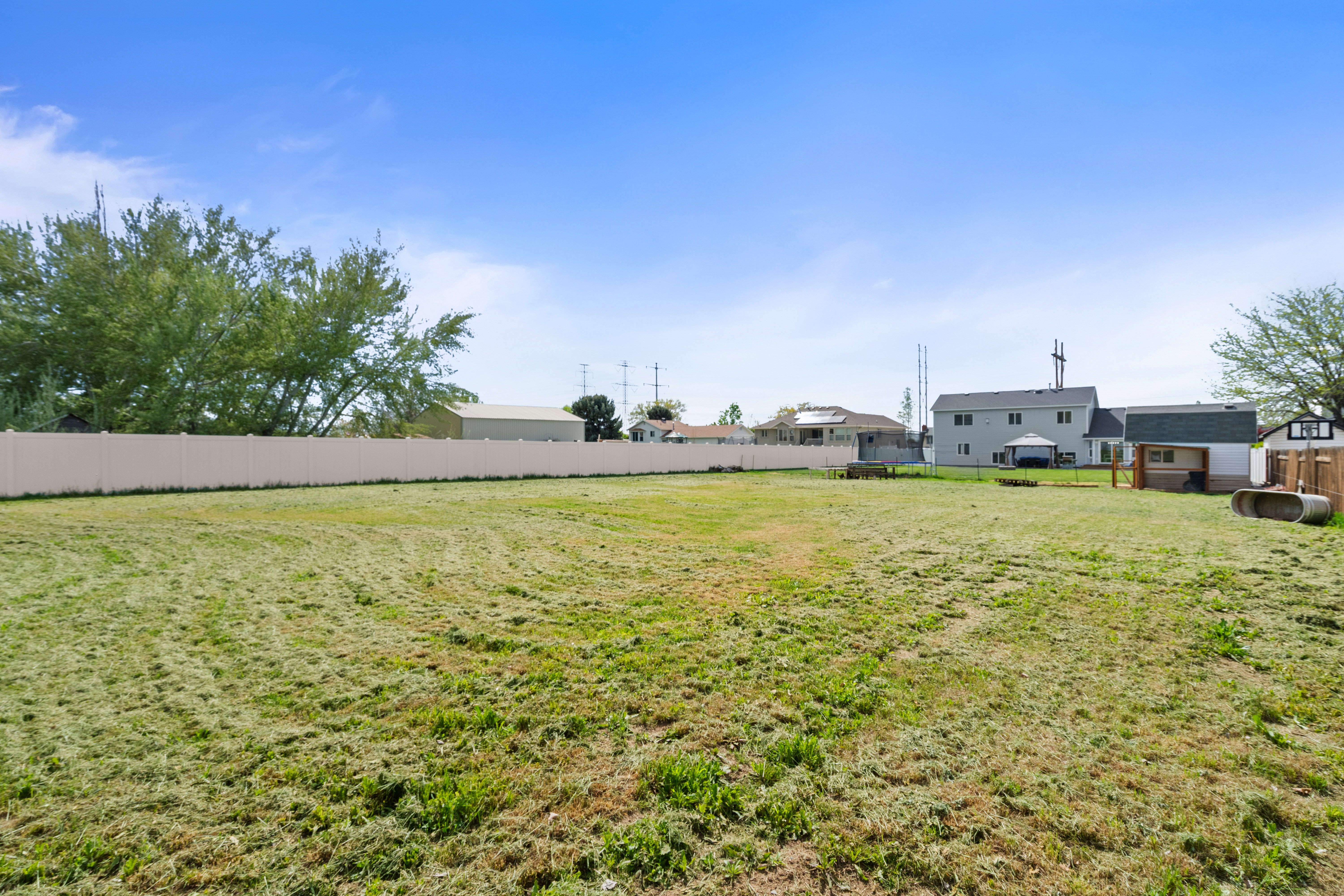 Expansive grass yard with a perimeter privacy fence