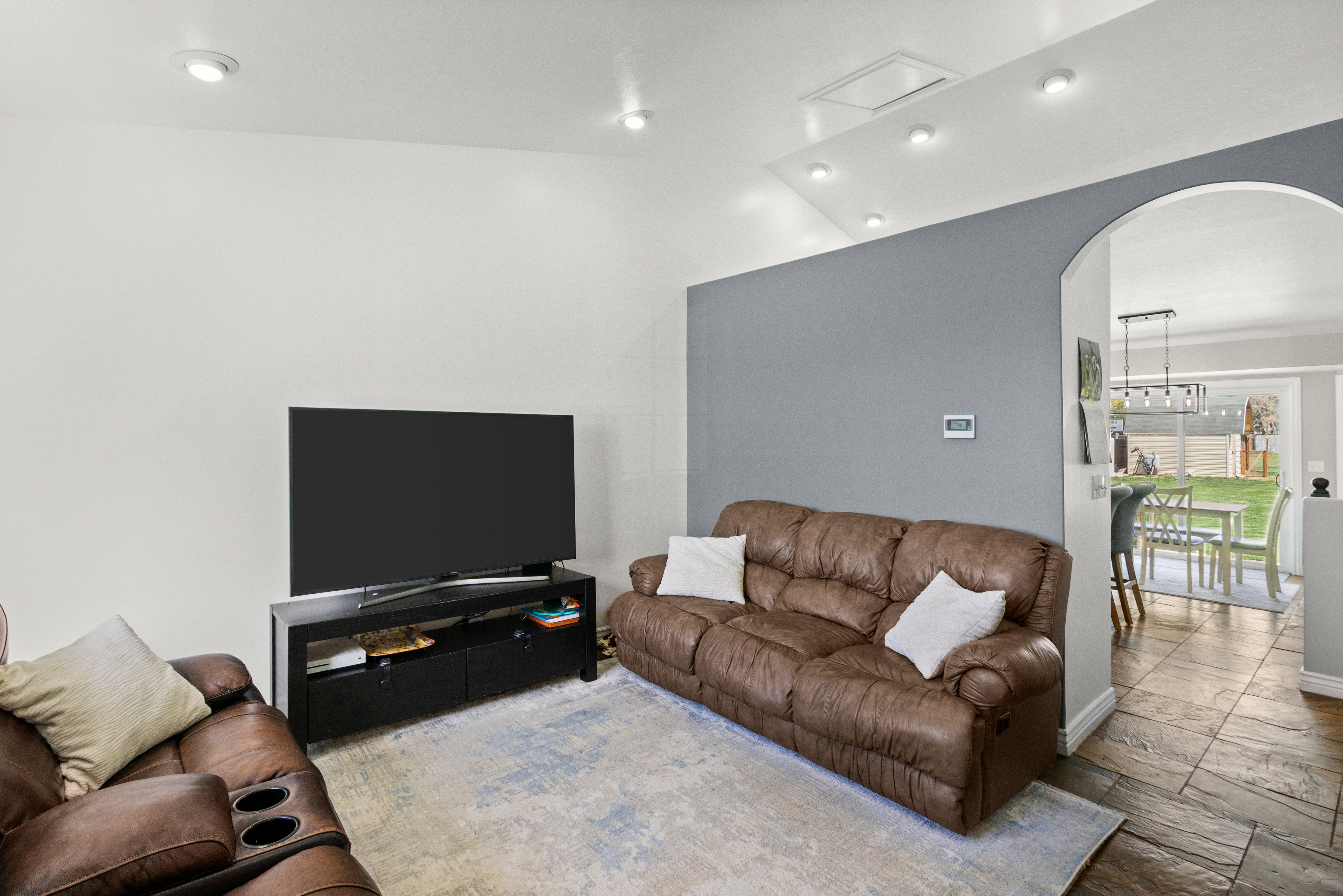 Recessed lighting illuminates this living space, featuring an arched doorway leading to an additional area