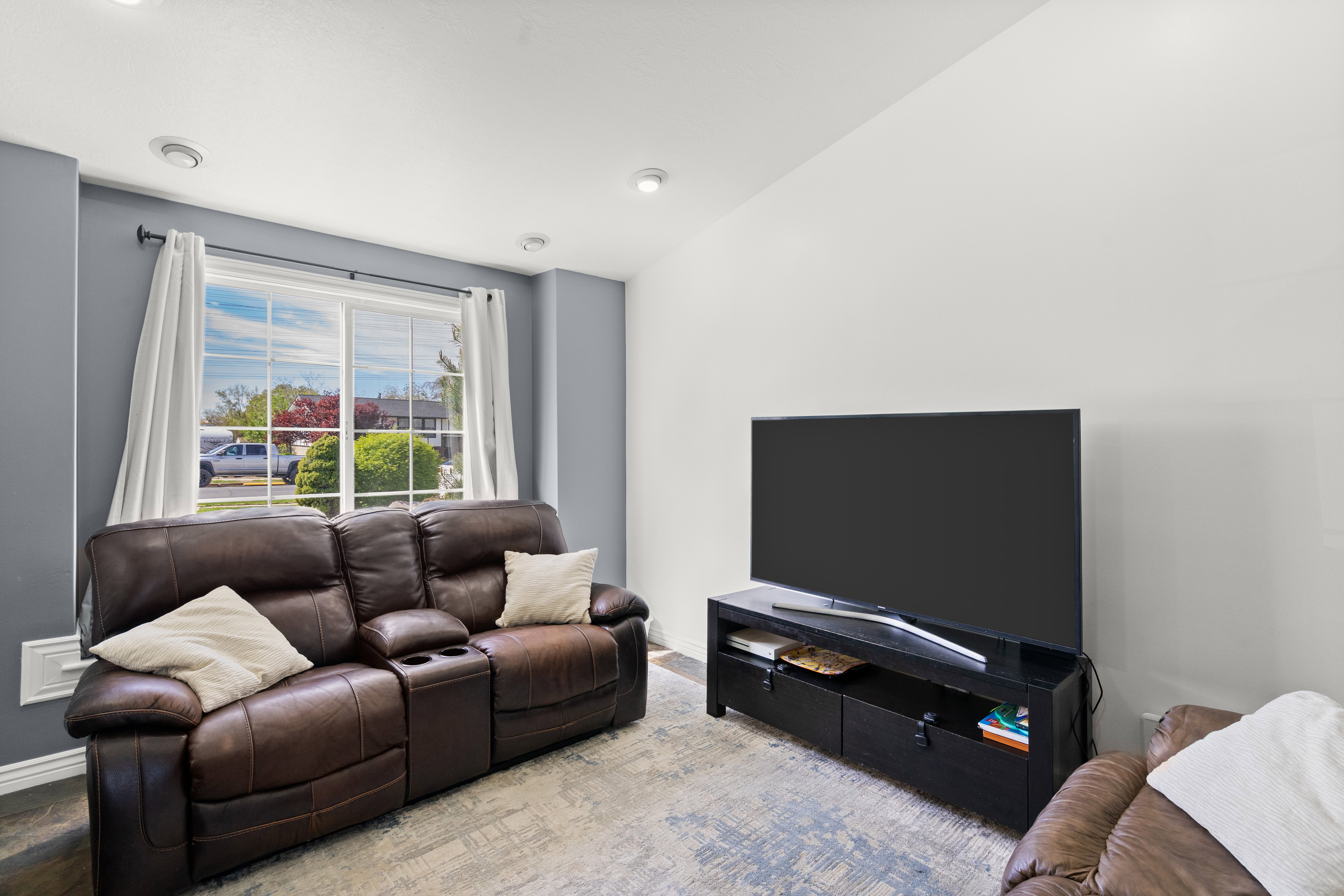 Living space featuring a large window with white trim, recessed lighting, and wood-finish flooring