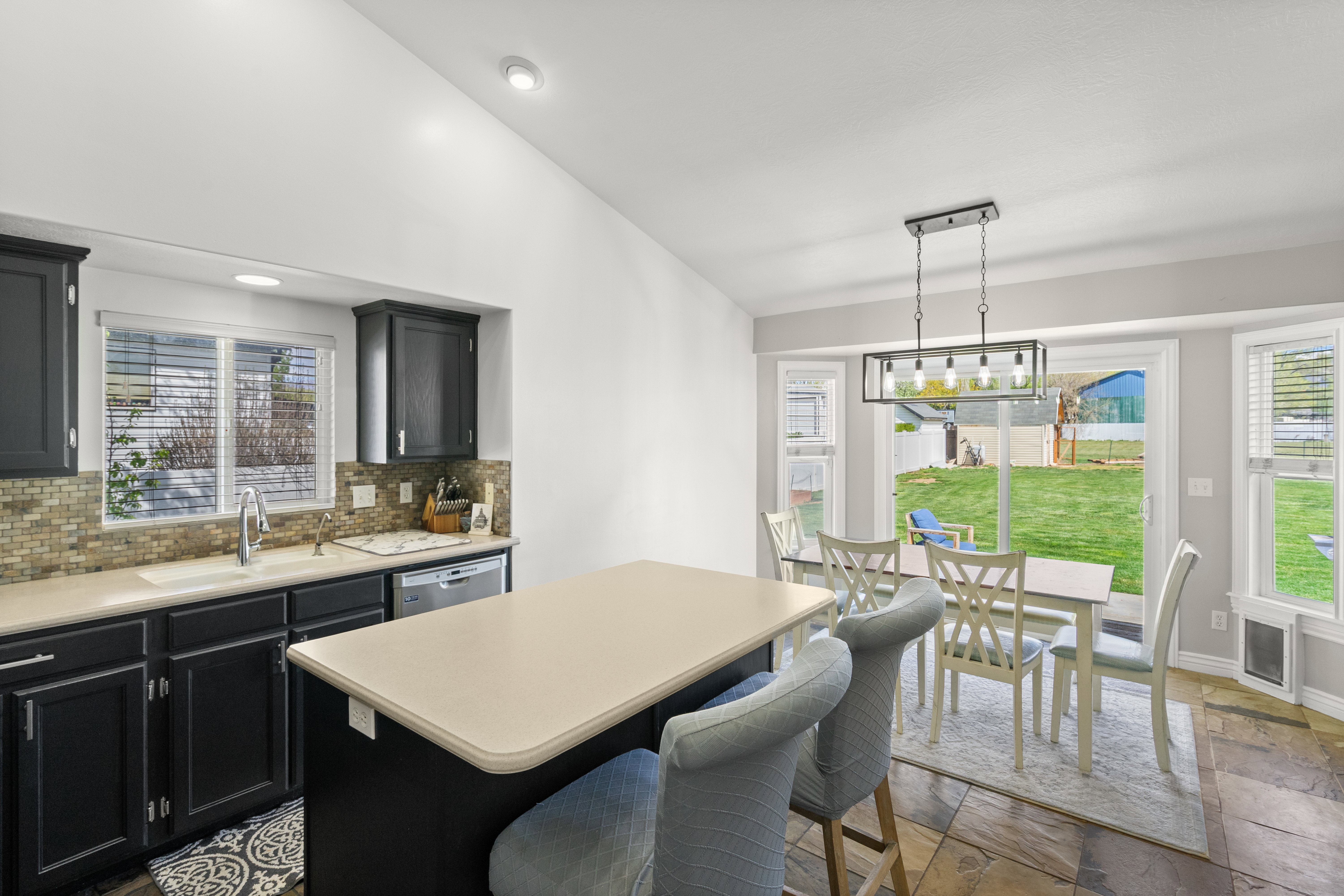 Kitchen featuring dark cabinetry, light countertops, and a mosaic tile backsplash