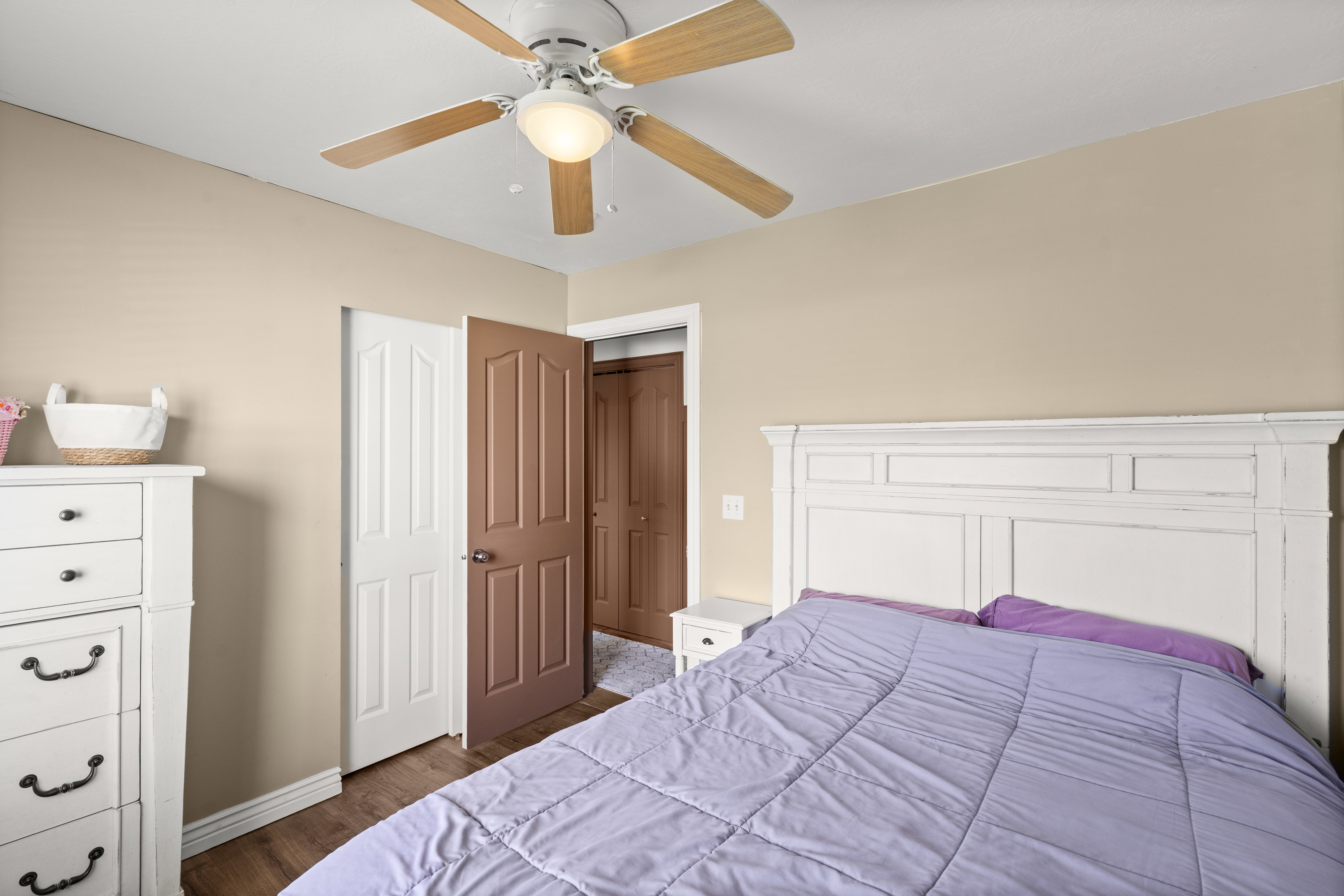 Bedroom featuring wood-finish flooring, a ceiling fan with integrated lighting, and neutral wall tones