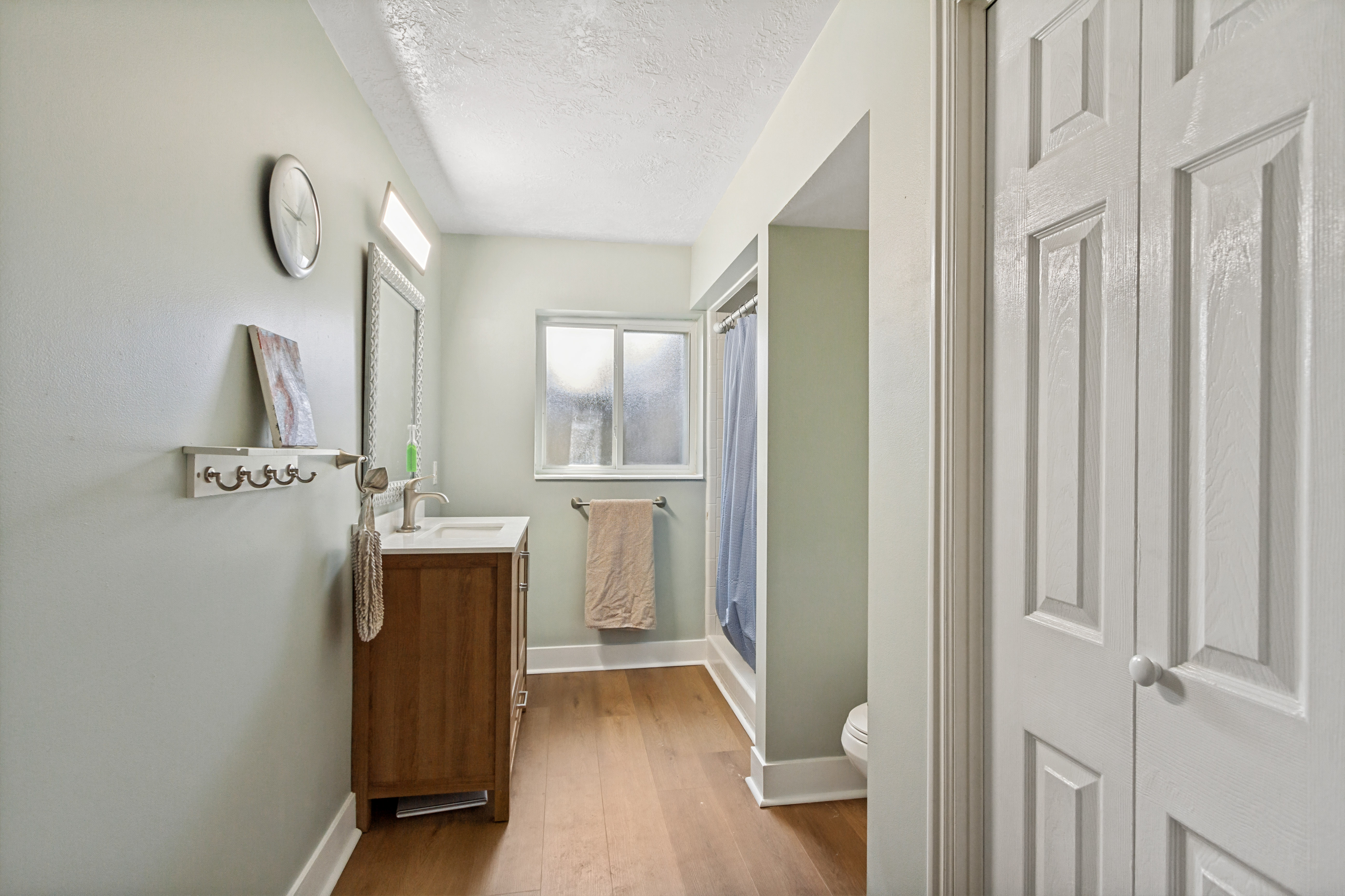 Bathroom featuring wood-finish flooring, a wood-finish vanity with an integrated sink, and a built-in shower enclosure