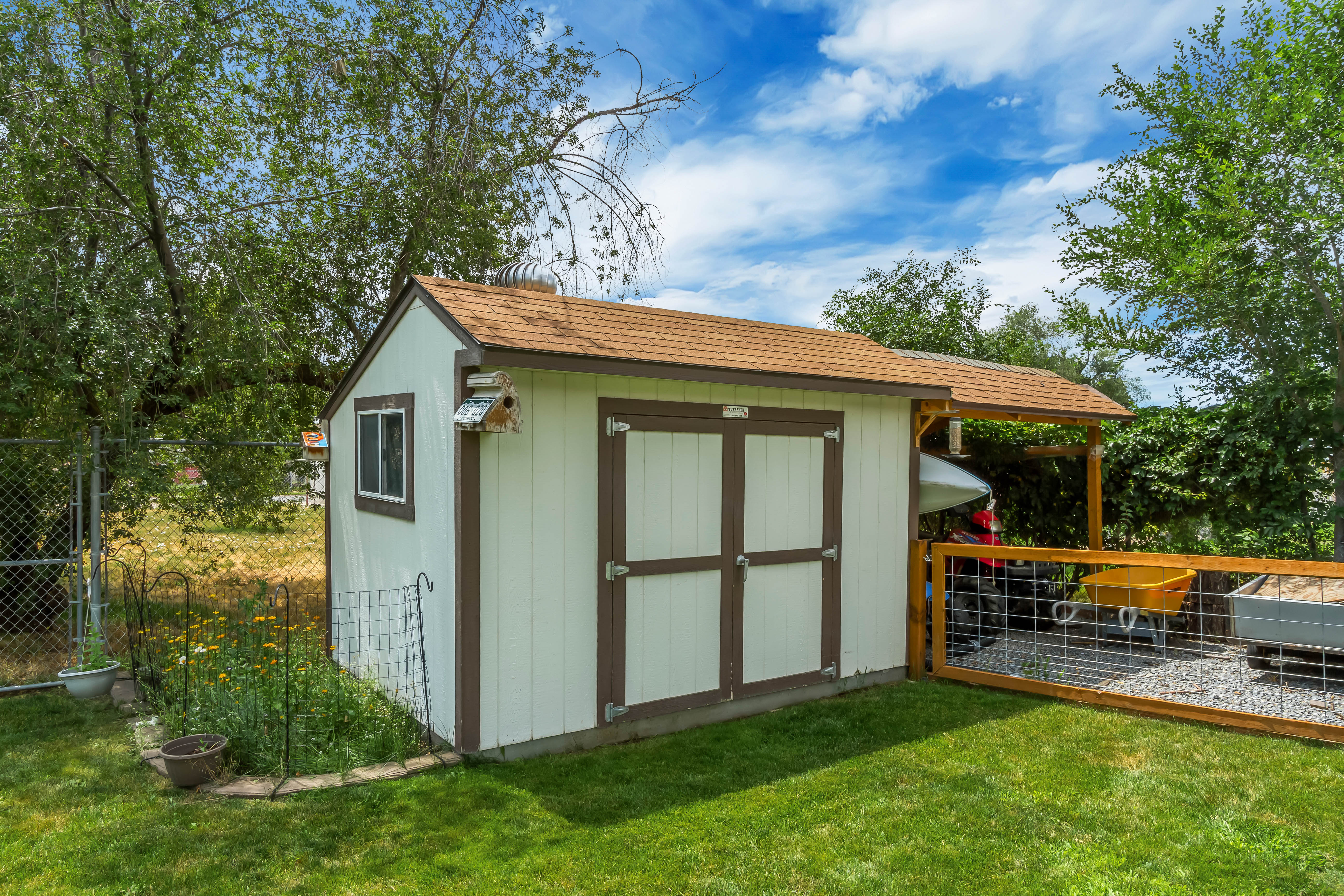 Detached storage shed featuring a shingle roof, double entry doors, side window, and an attached covered lean-to structure