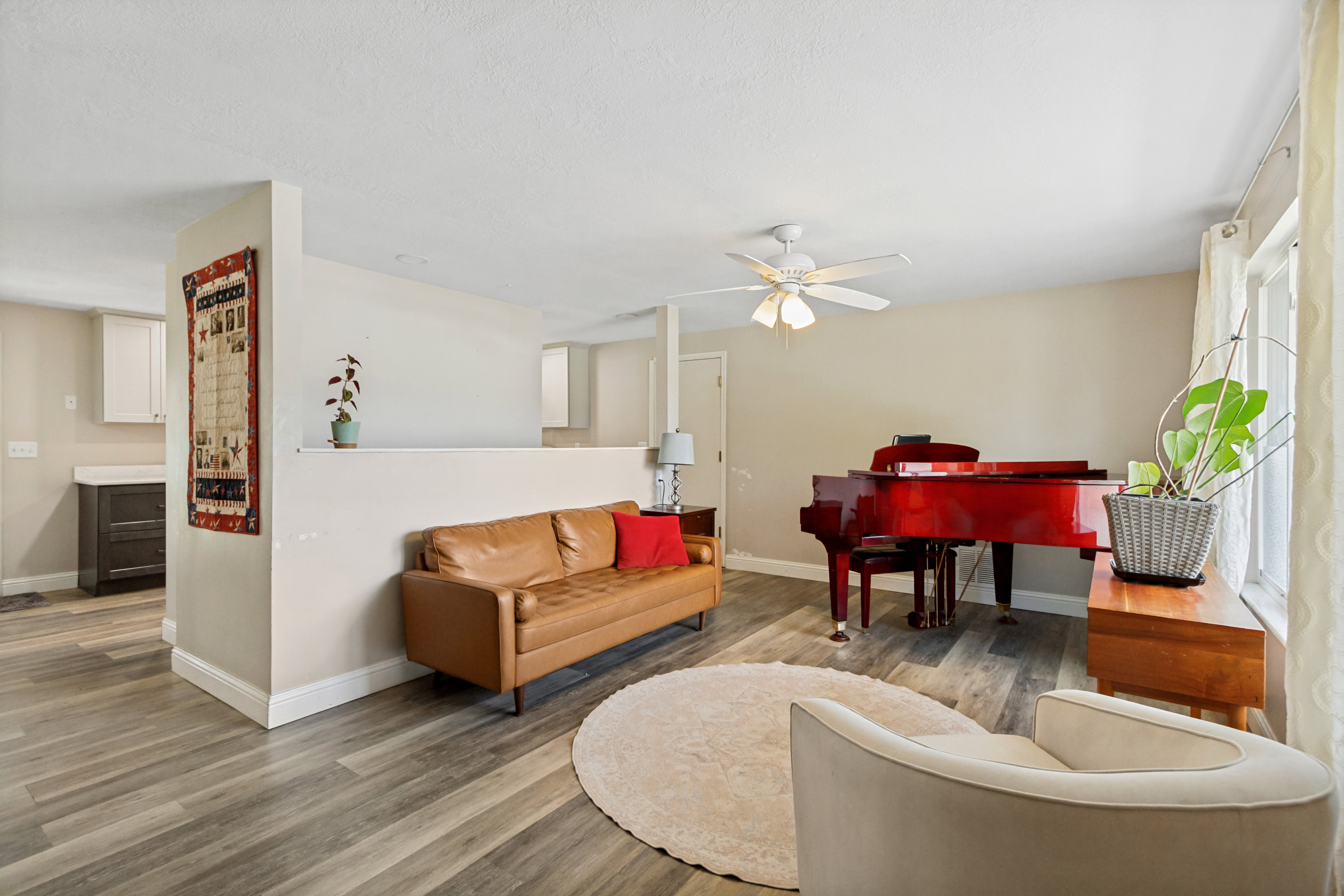 Open-concept living space featuring wood-finish flooring, a ceiling fan, and abundant natural light from a large window