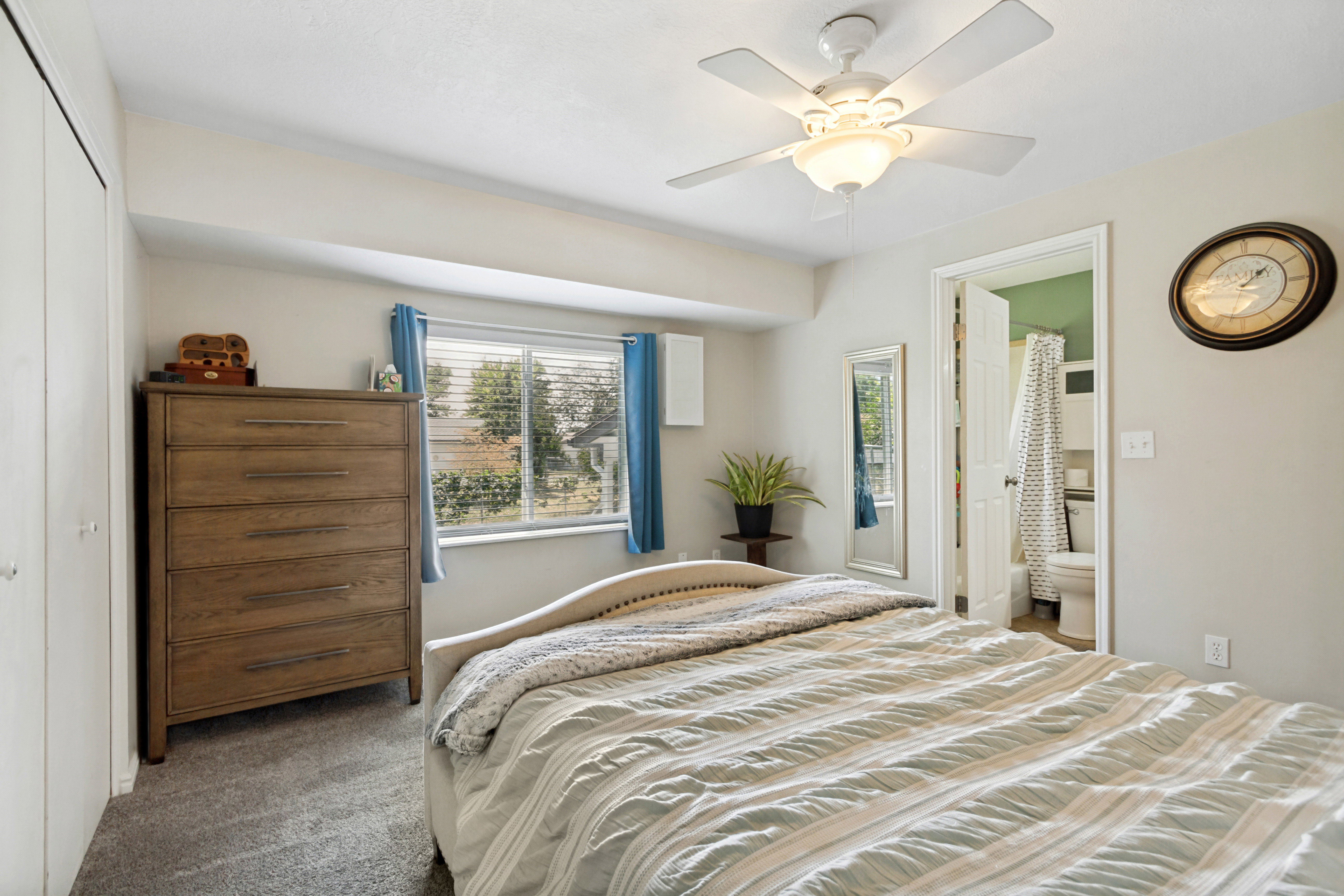 Neutral-toned bedroom featuring wall-to-wall carpeting and a ceiling fan with integrated lighting