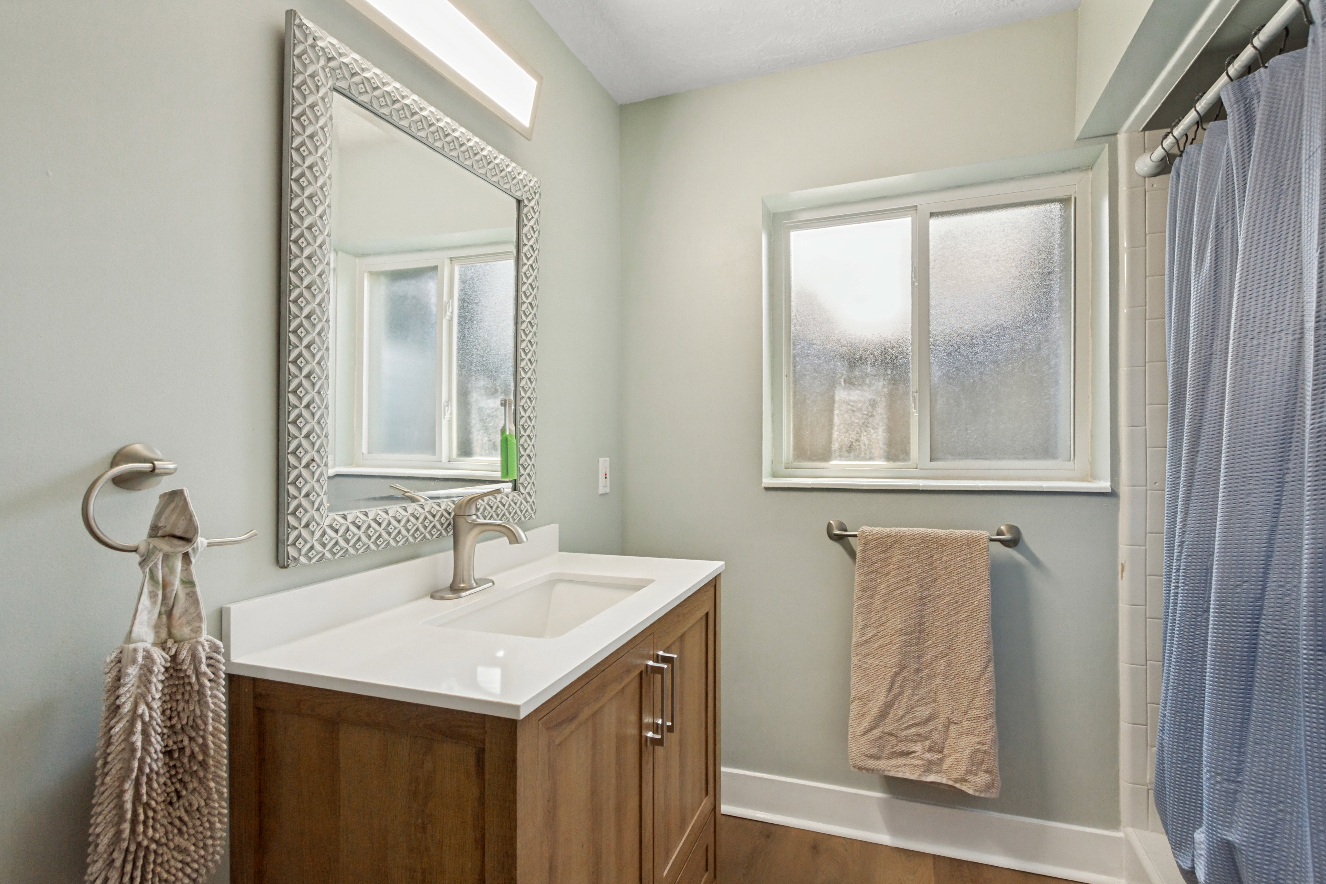 Bathroom featuring a wood-finish vanity with a white countertop and rectangular sink