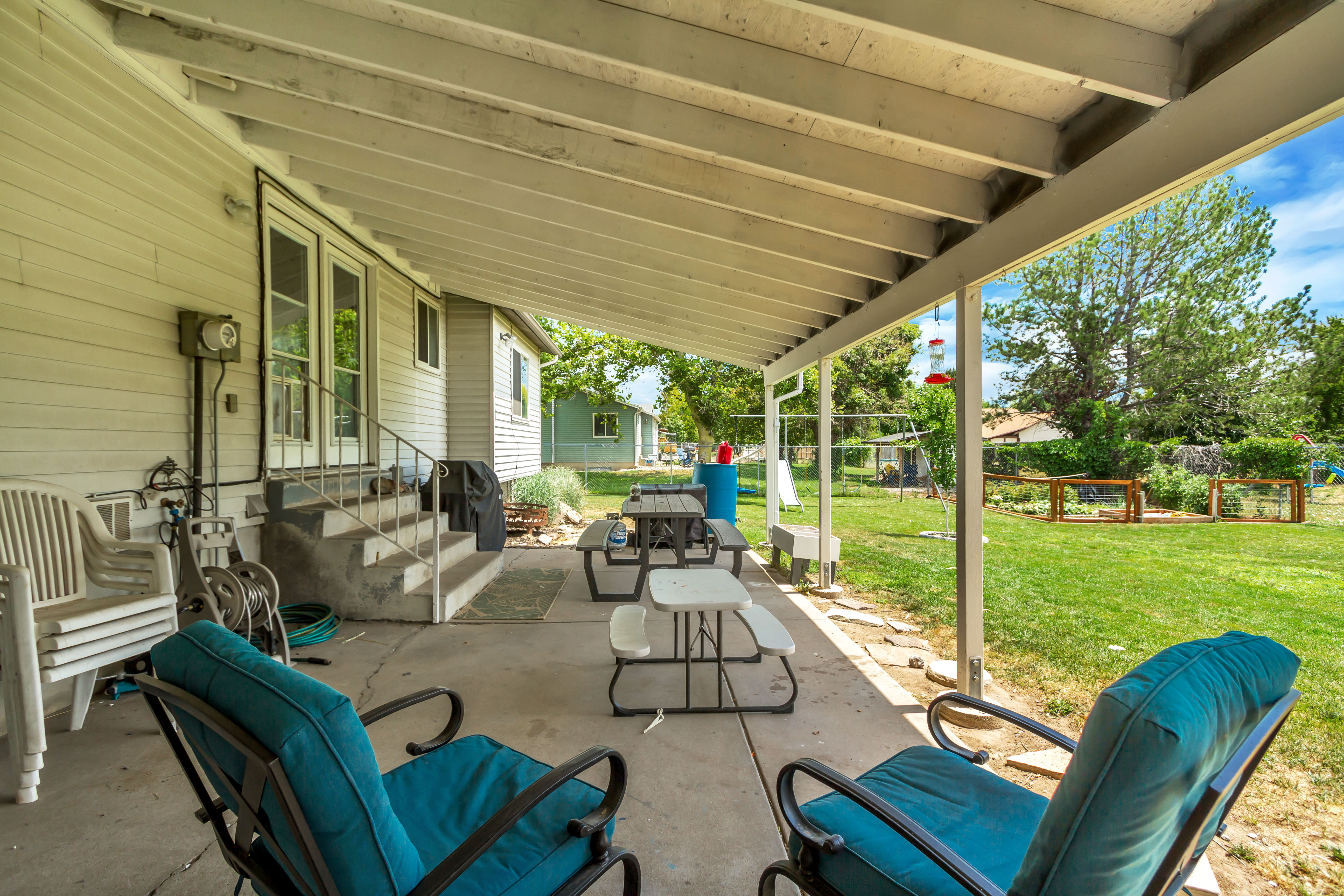 Covered patio with a concrete slab, providing access to the expansive green lawn