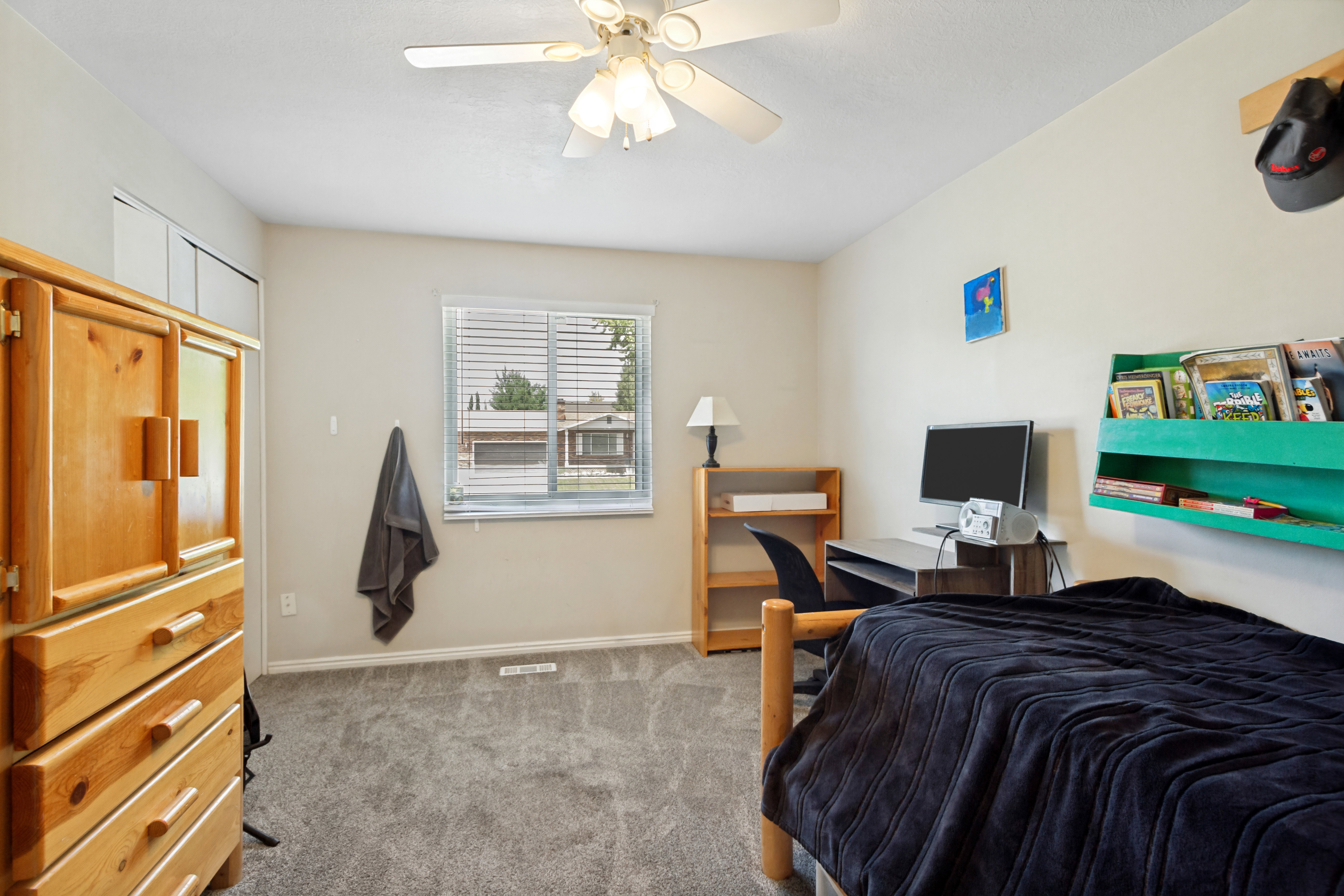 Carpeted room featuring a window with blinds, ceiling fan, and light-toned walls