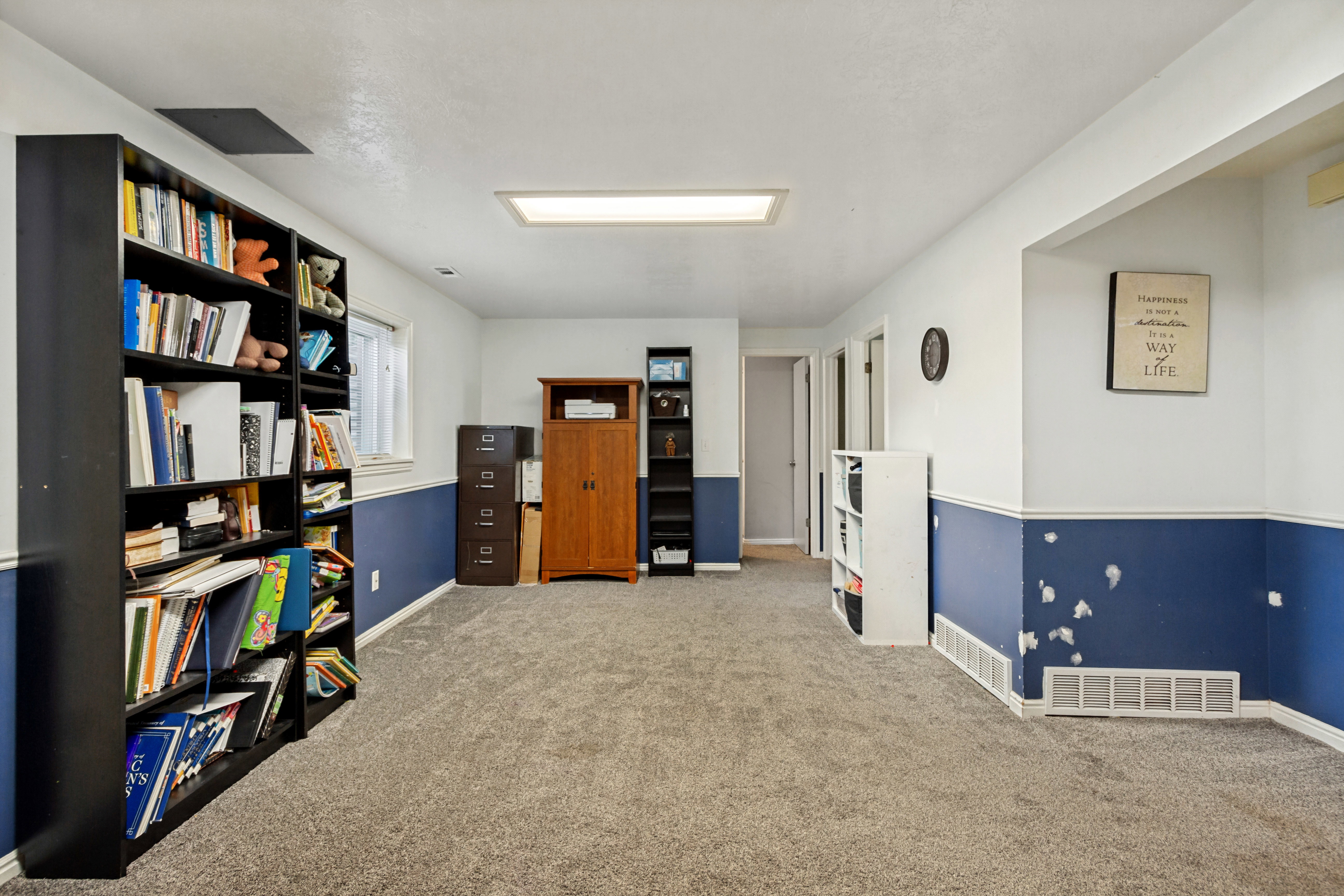 Carpeted room with white and blue two-tone walls, featuring a rectangular ceiling light fixture