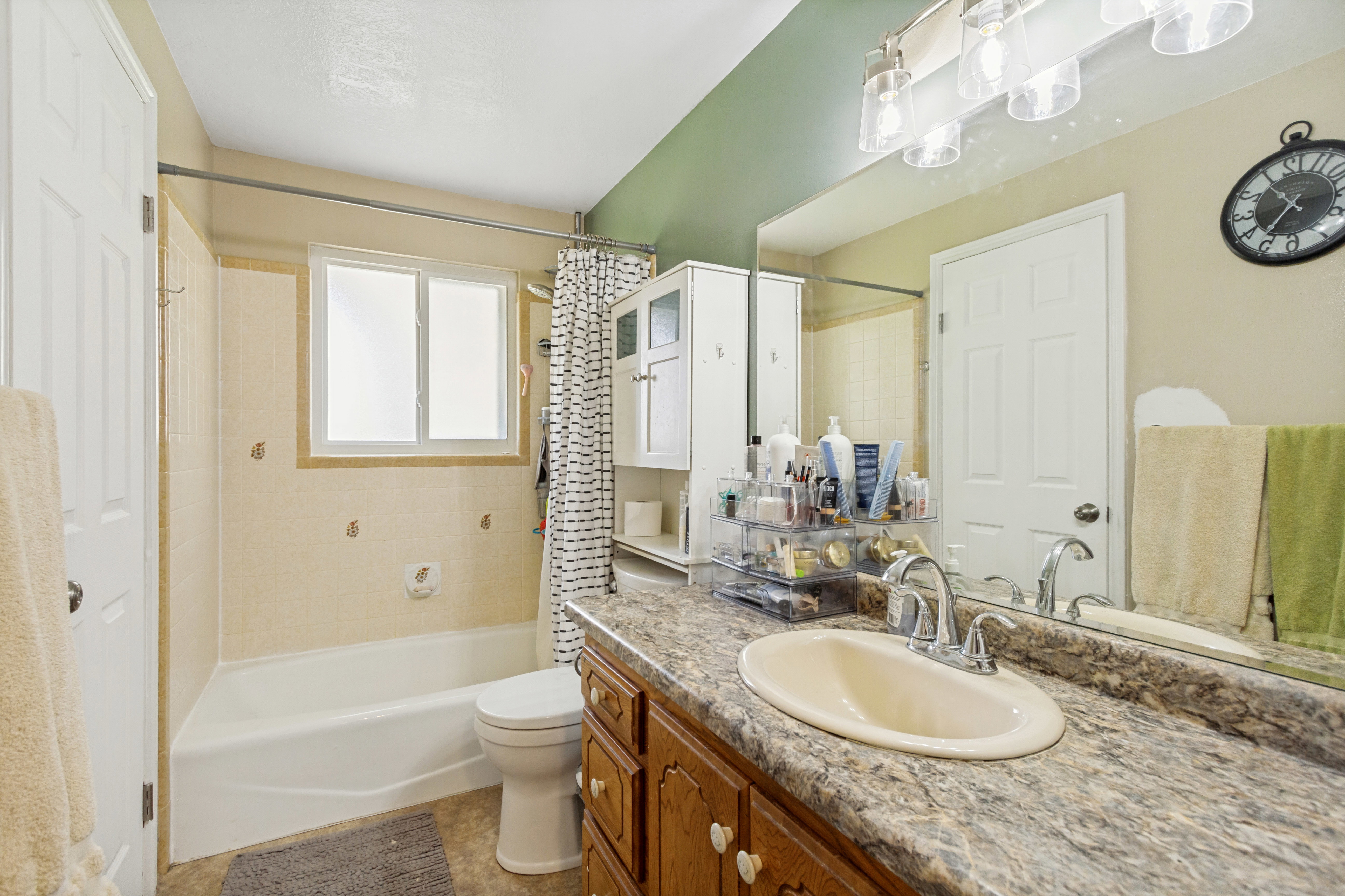 Bathroom featuring a built-in tub with a shower, a vanity with an integrated sink, and a large wall mirror